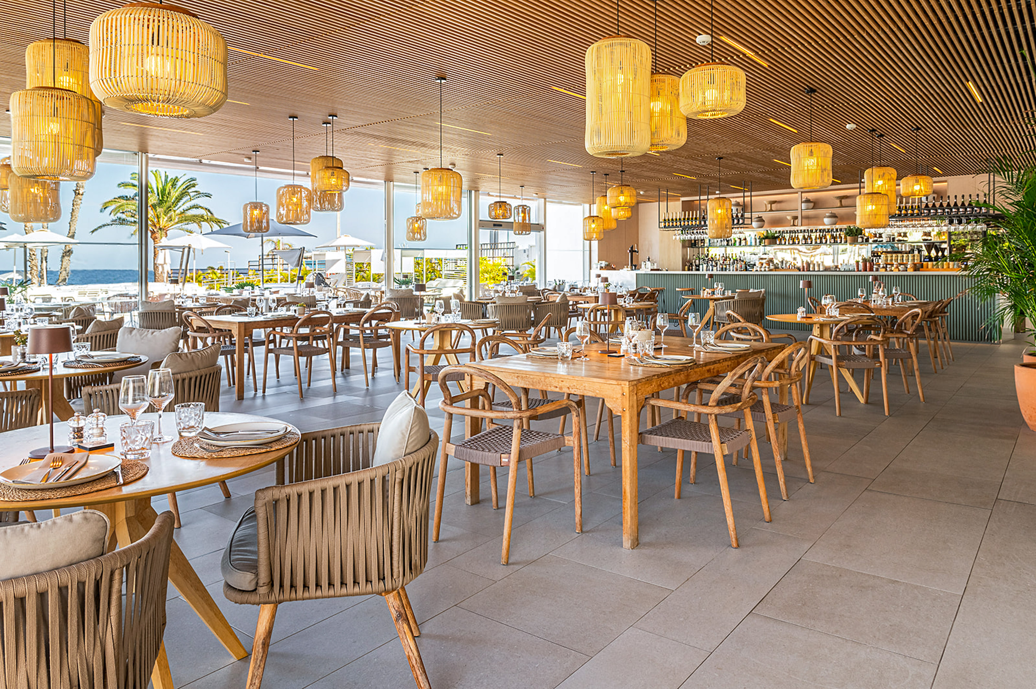 Mediterranean restaurant interior, sea view, wooden tables, rattan lights.