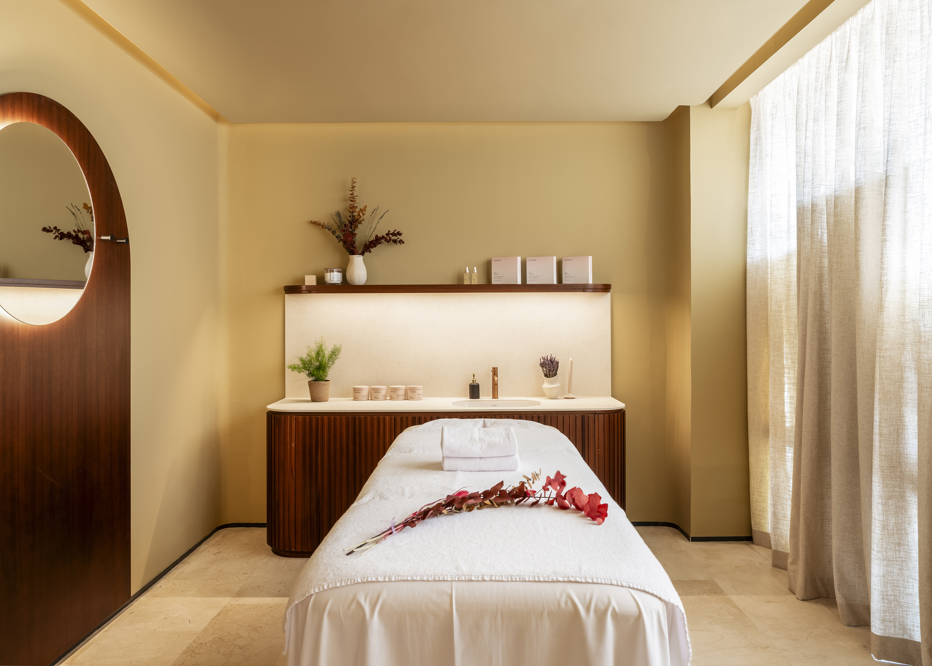 Spa massage room with treatment bed, wellness products, and warm decor.
