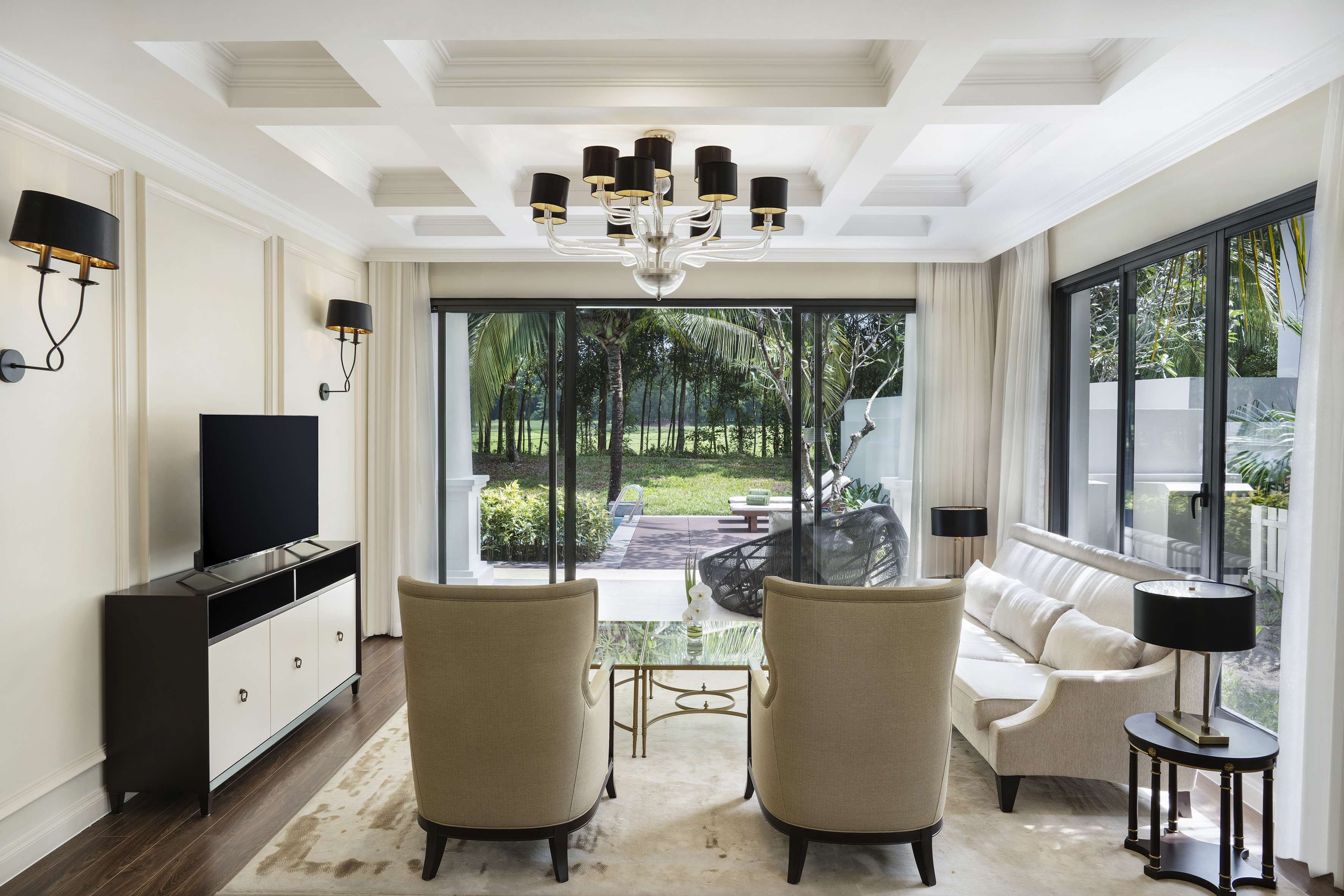 Modern luxury living room with tropical garden view through sliding doors.
