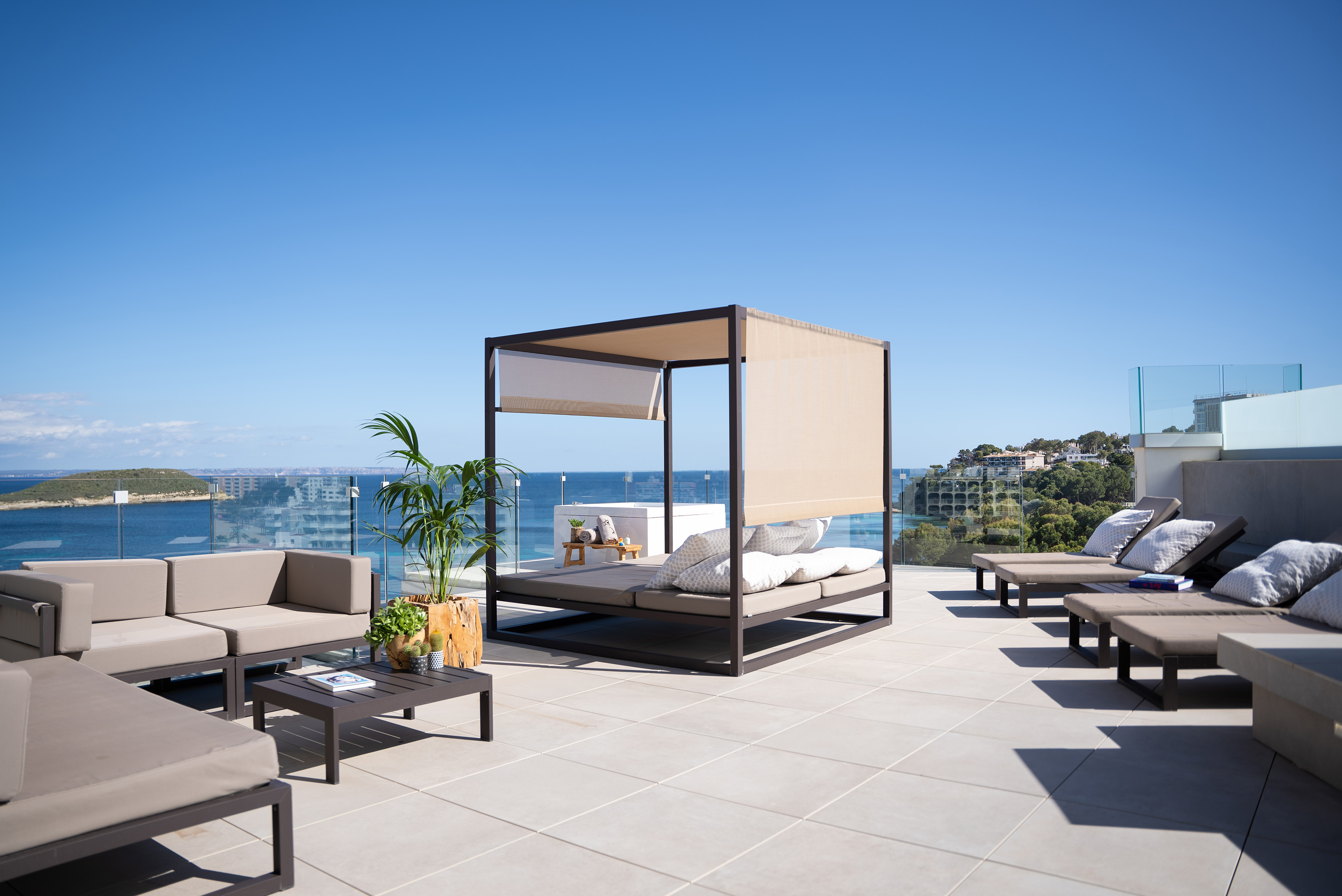 Rooftop terrace with daybed, outdoor lounge, sun loungers, and ocean view.