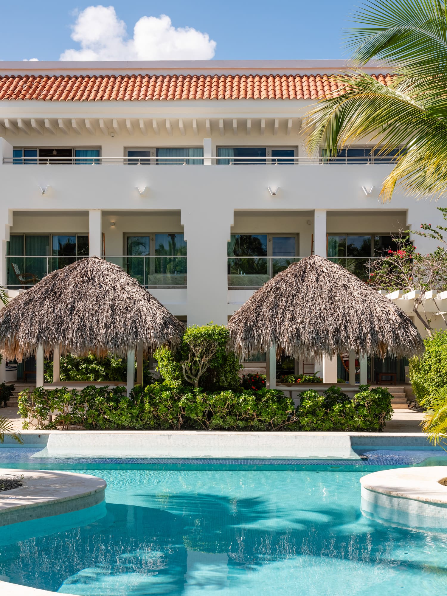 a pool with palm trees and a building with a roof