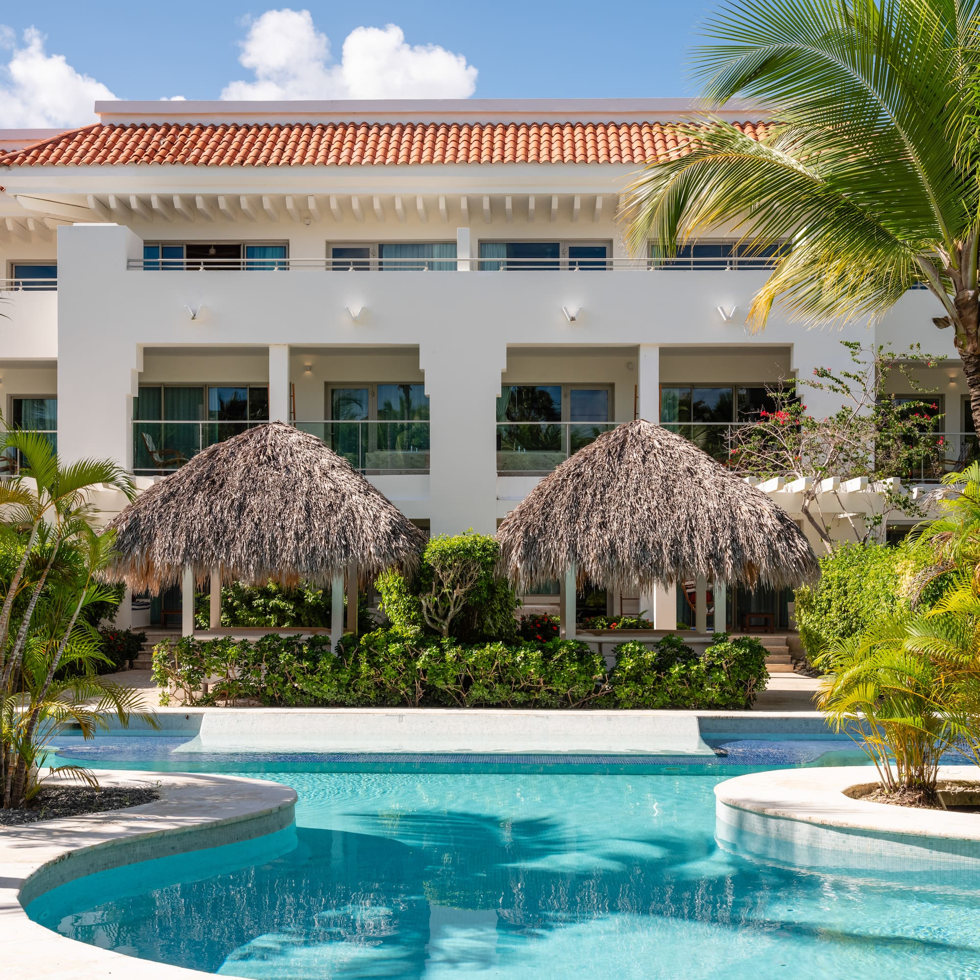 a pool with palm trees and a building with a roof