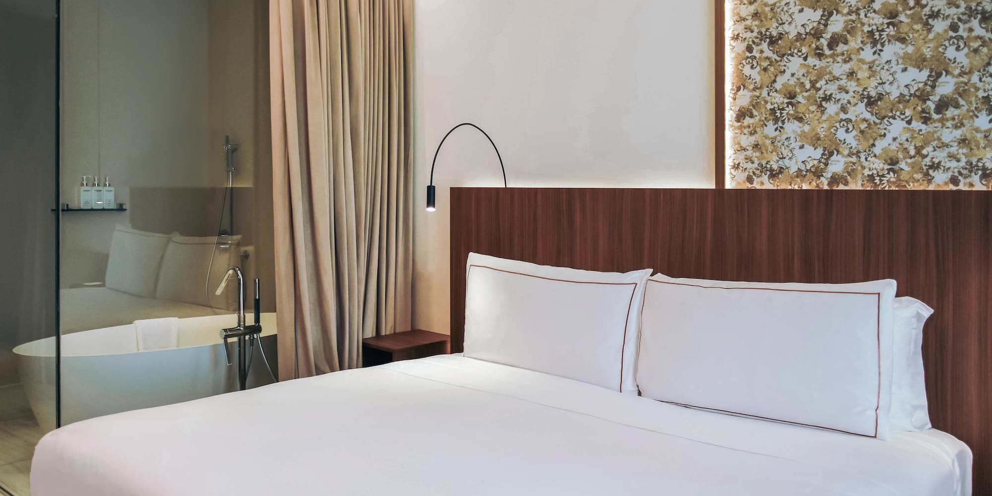 Twin bed with white sheets and a bathtub at the standard room from the Palazzo Cordusio Gran Melia Hotel