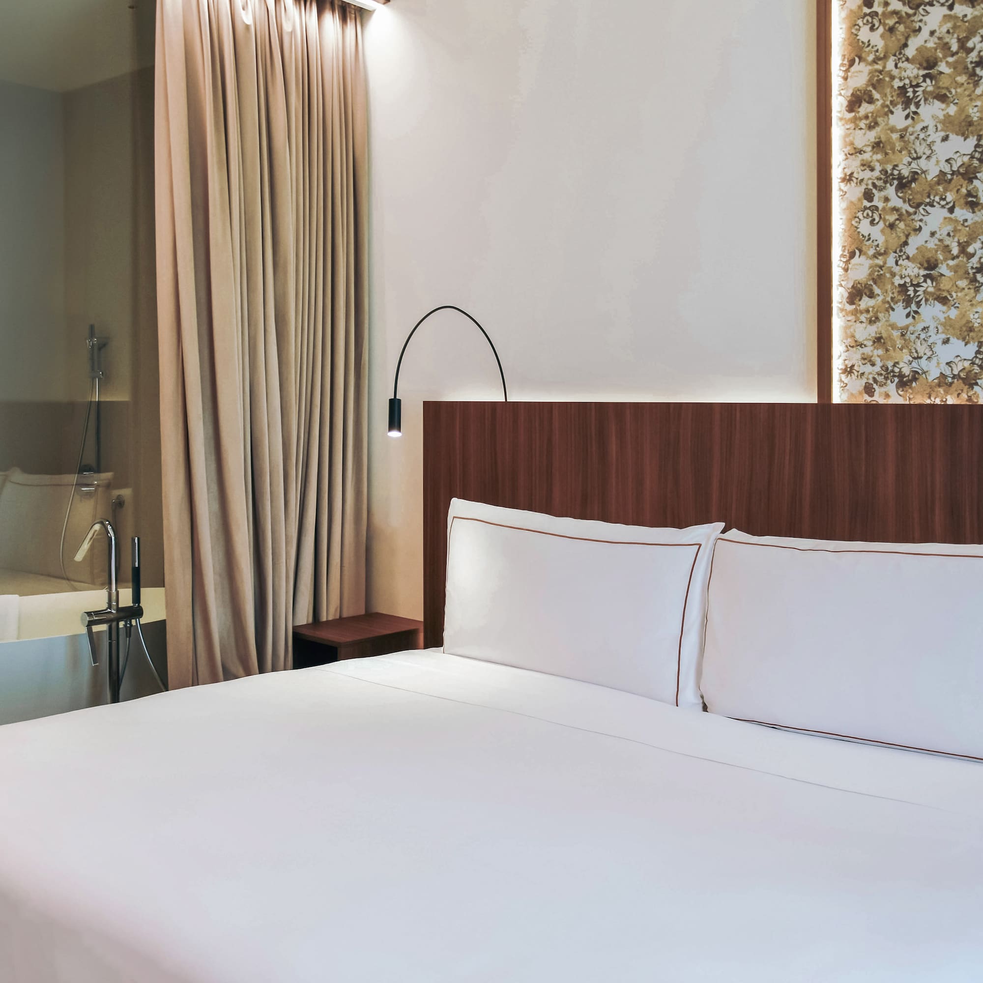 Twin bed with white sheets and a bathtub at the standard room from the Palazzo Cordusio Gran Melia Hotel