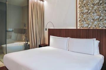 Twin bed with white sheets and a bathtub at the standard room from the Palazzo Cordusio Gran Melia Hotel