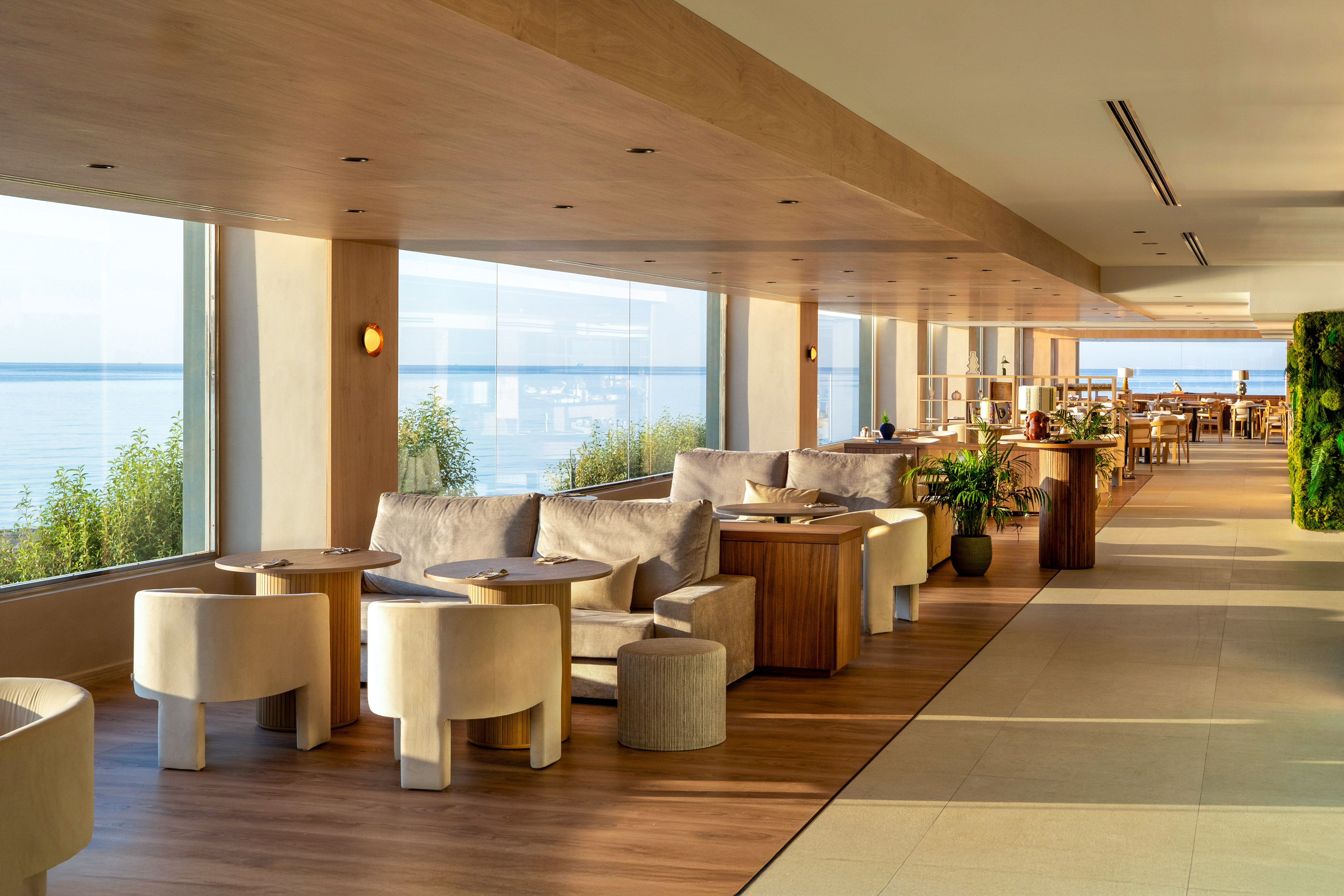 Modern hotel lounge with ocean view, contemporary sofas, and natural wood accents.