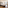 Bright modern hotel room with twin beds, wooden floor, large window, and work desk.