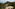 Coastal resort with tennis courts, green hills, and sea view.
