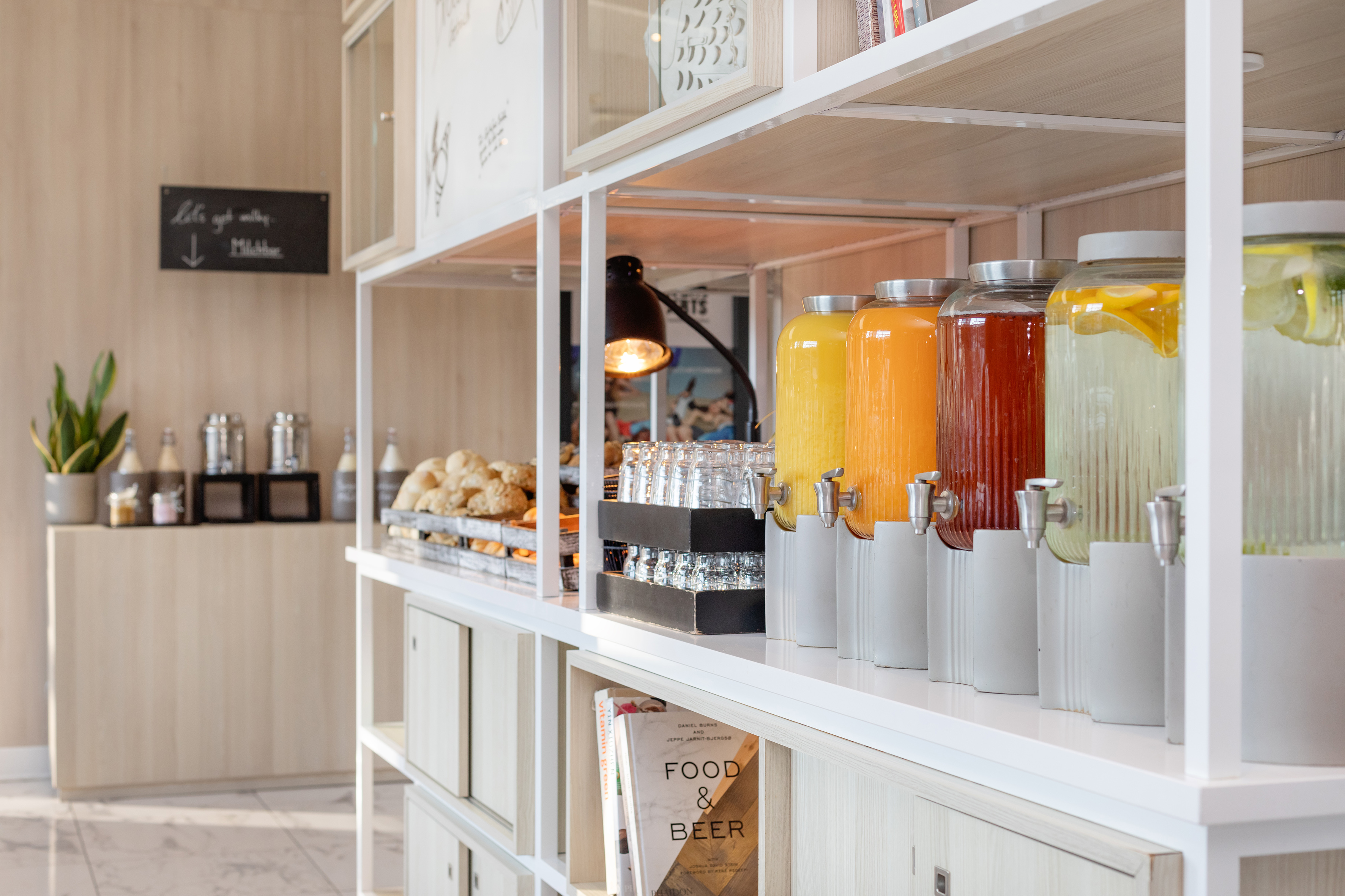 Breakfast buffet with juice dispensers, infused water, glasses, and pastries.