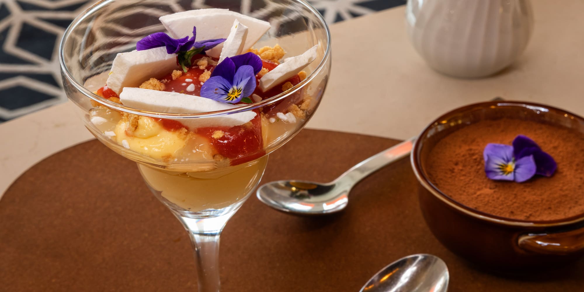 Layered fruit parfait with meringue, pansies, and chocolate mousse dessert.