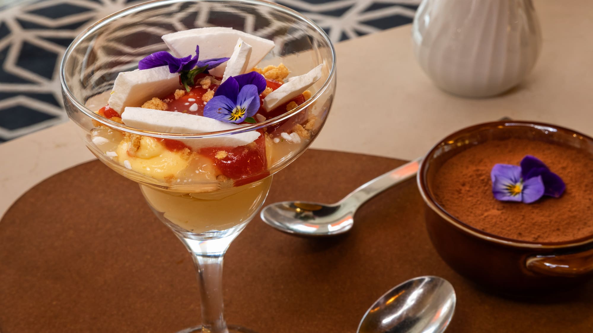 Layered fruit parfait with meringue, pansies, and chocolate mousse dessert.