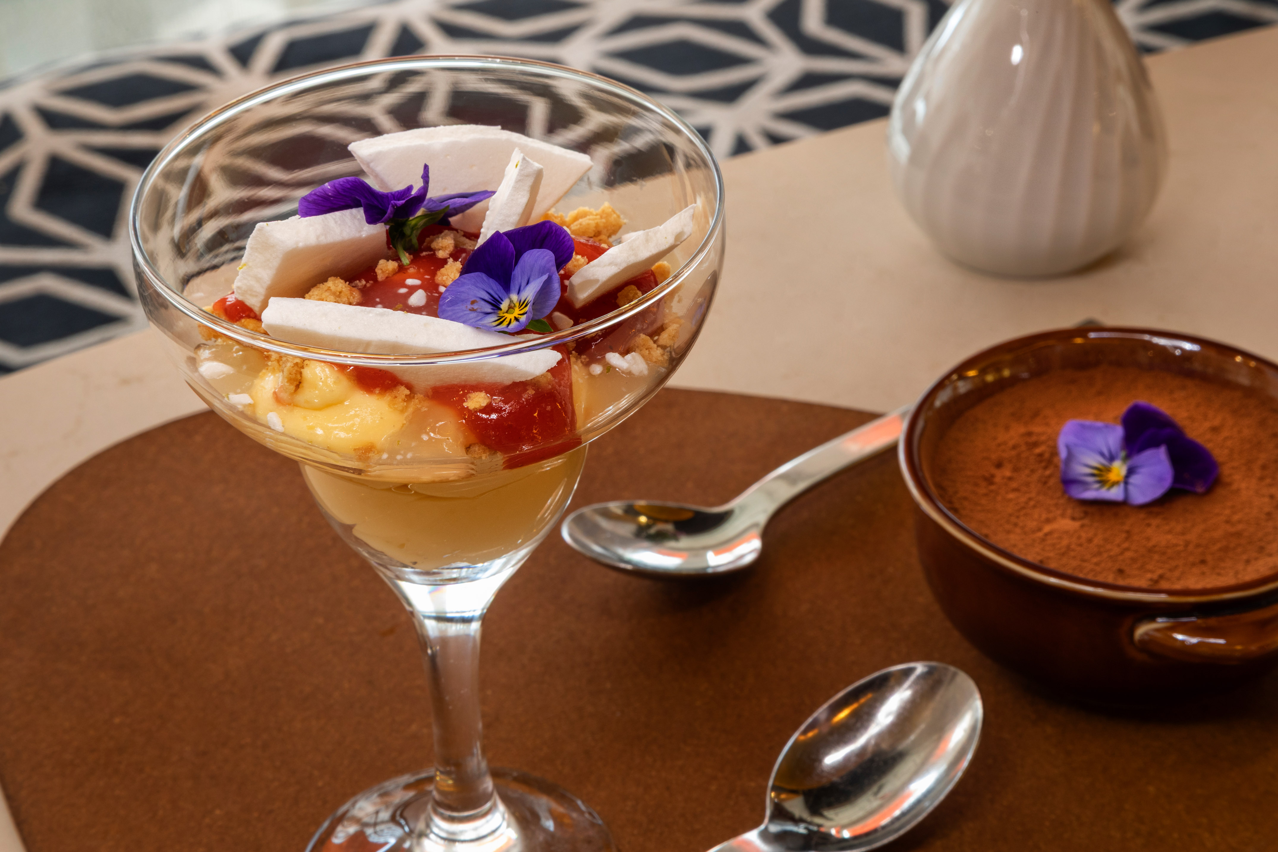 Layered fruit parfait with meringue, pansies, and chocolate mousse dessert.