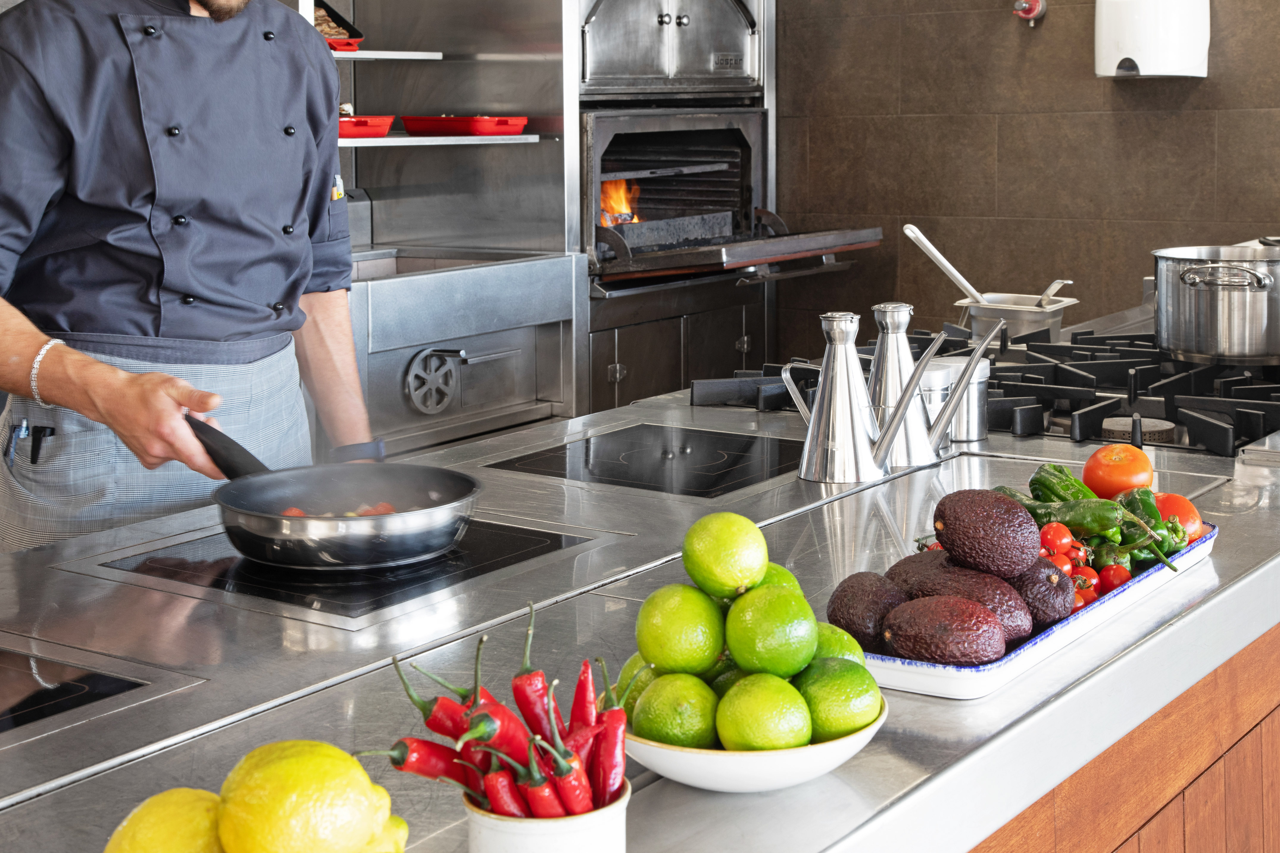 Chef cooking with fresh avocados, limes, chili in a professional kitchen.