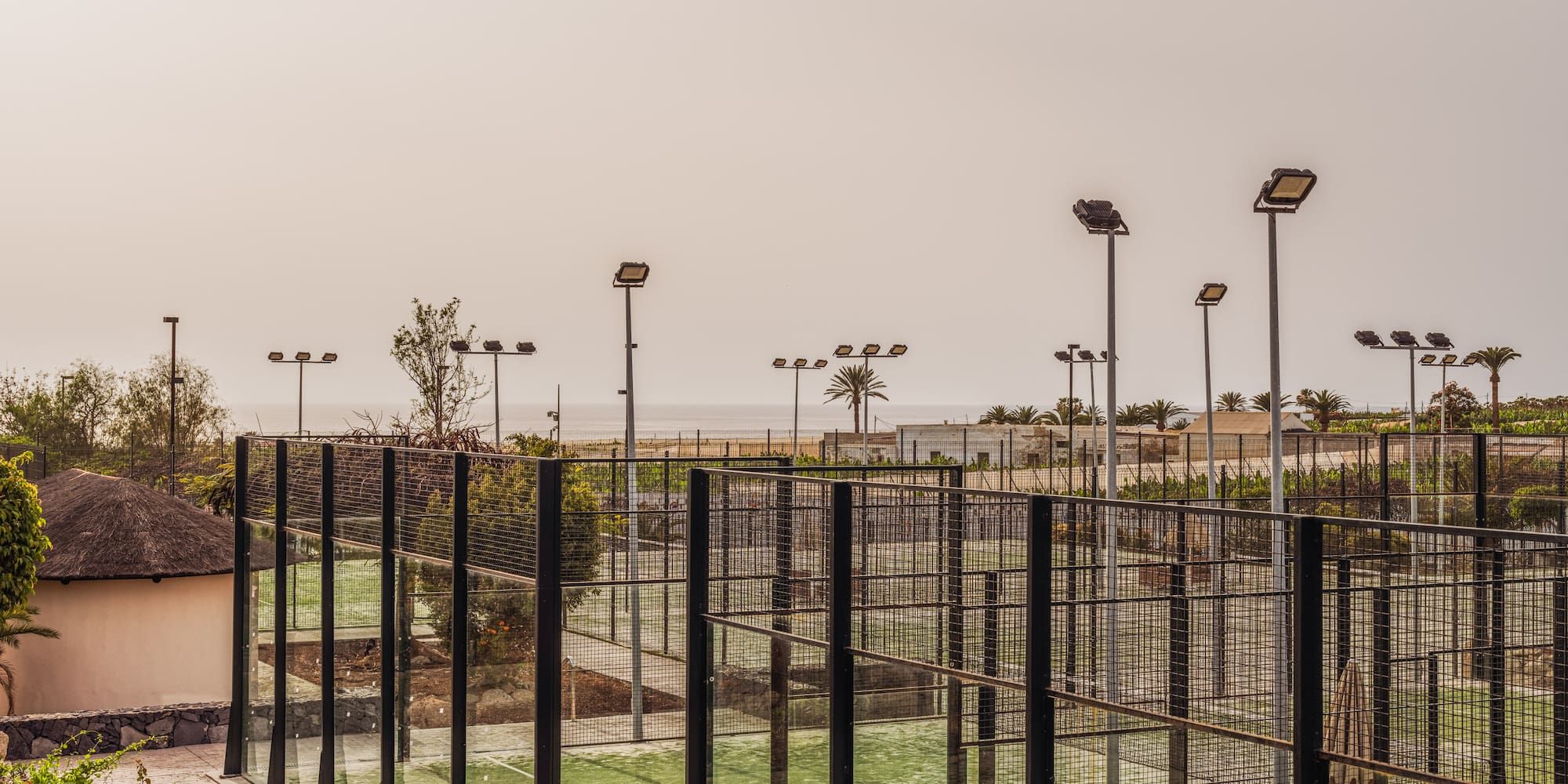 a tennis court with lights and trees
