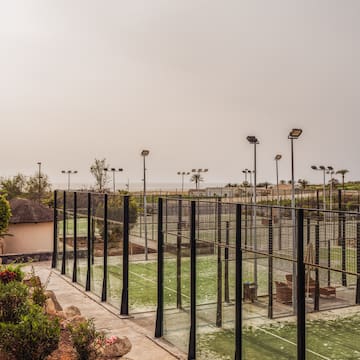 a tennis court with lights and trees