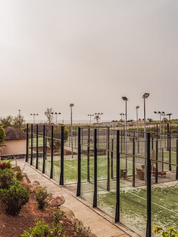 a tennis court with lights and trees