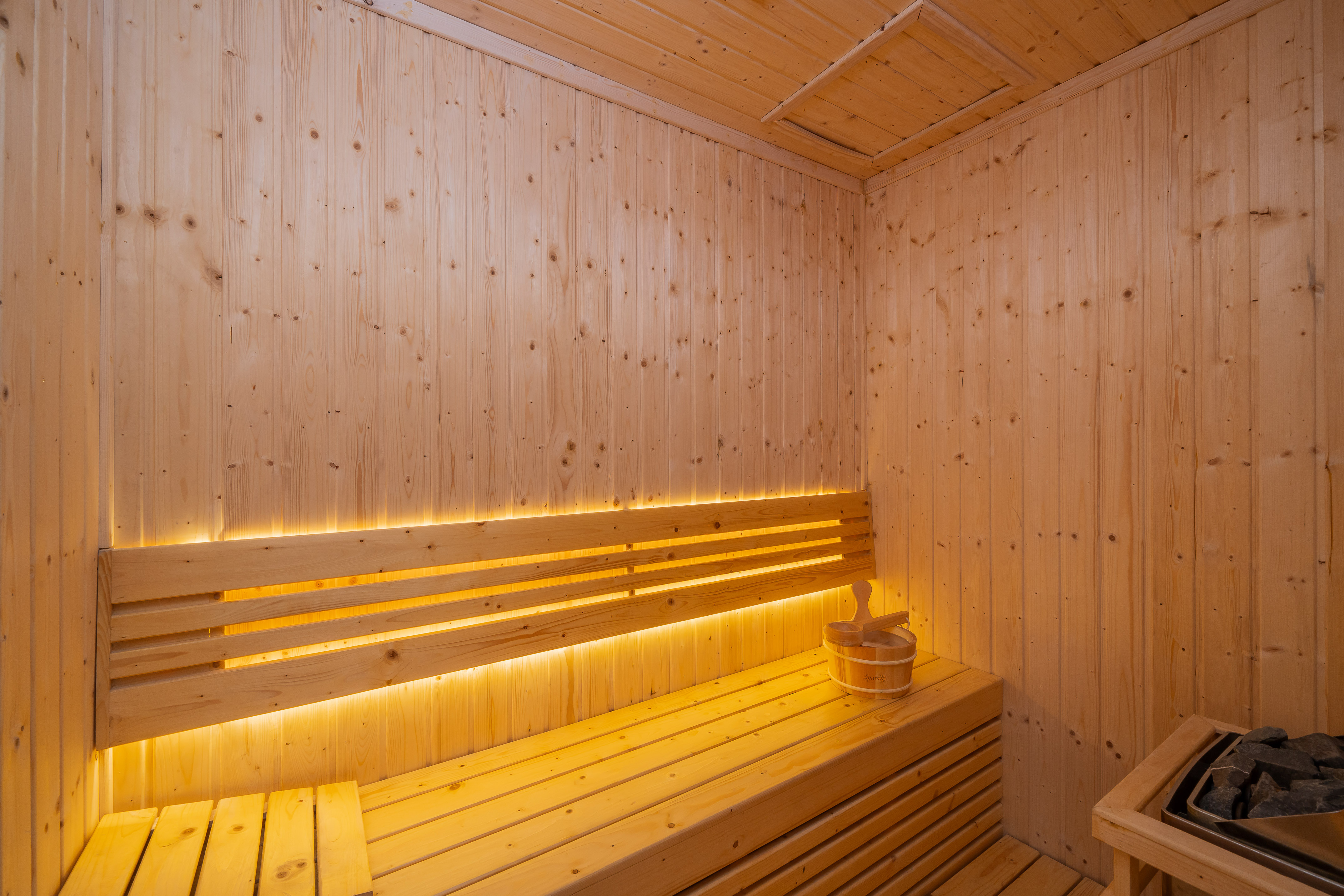 Wooden sauna interior with bench, LED lighting, bucket, and heater. - YHI Spa - Meliá Pattaya Hotel, Pattaya