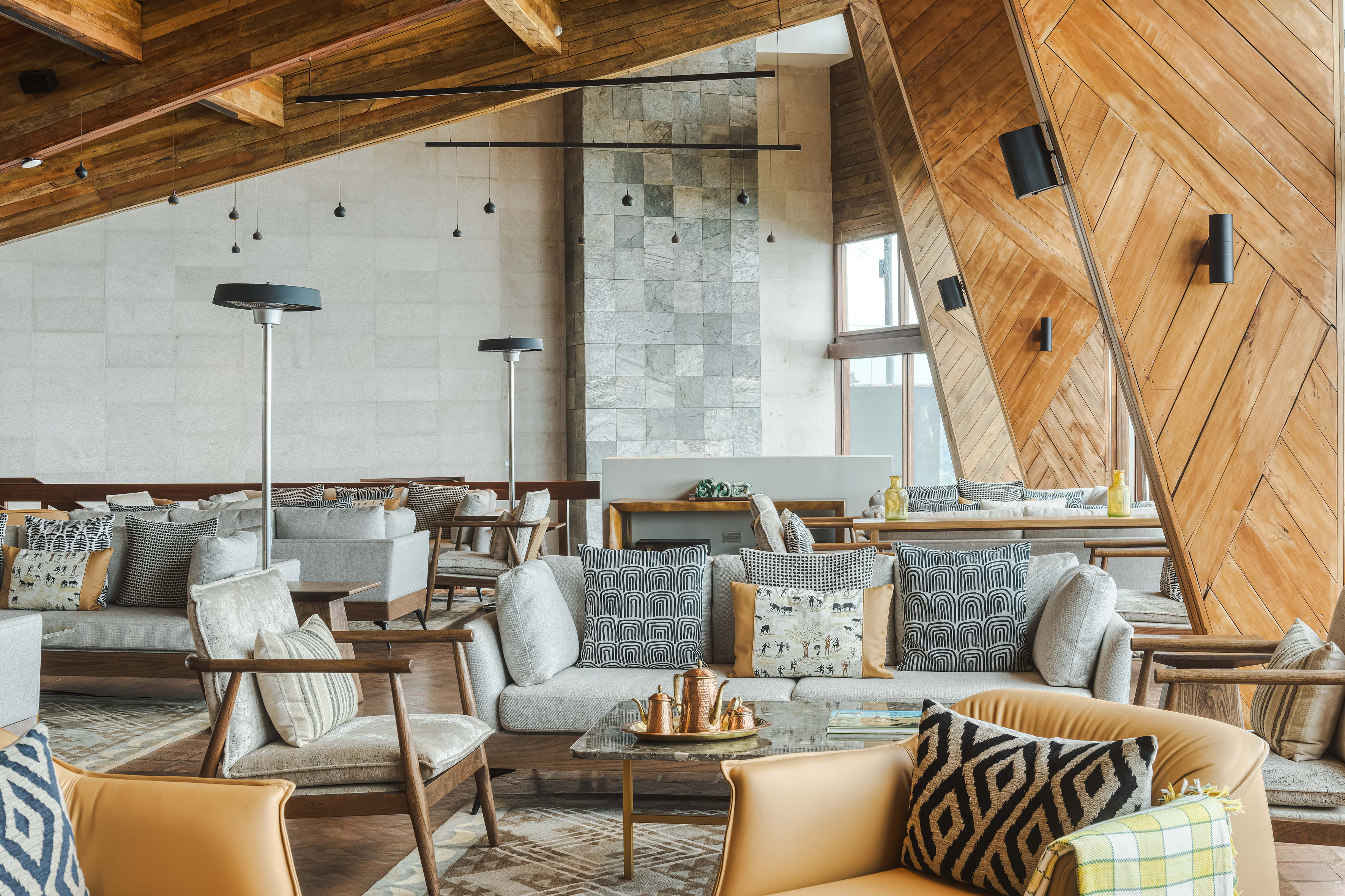 Luxury hotel lounge with wooden beams, stone wall, and contemporary seating.