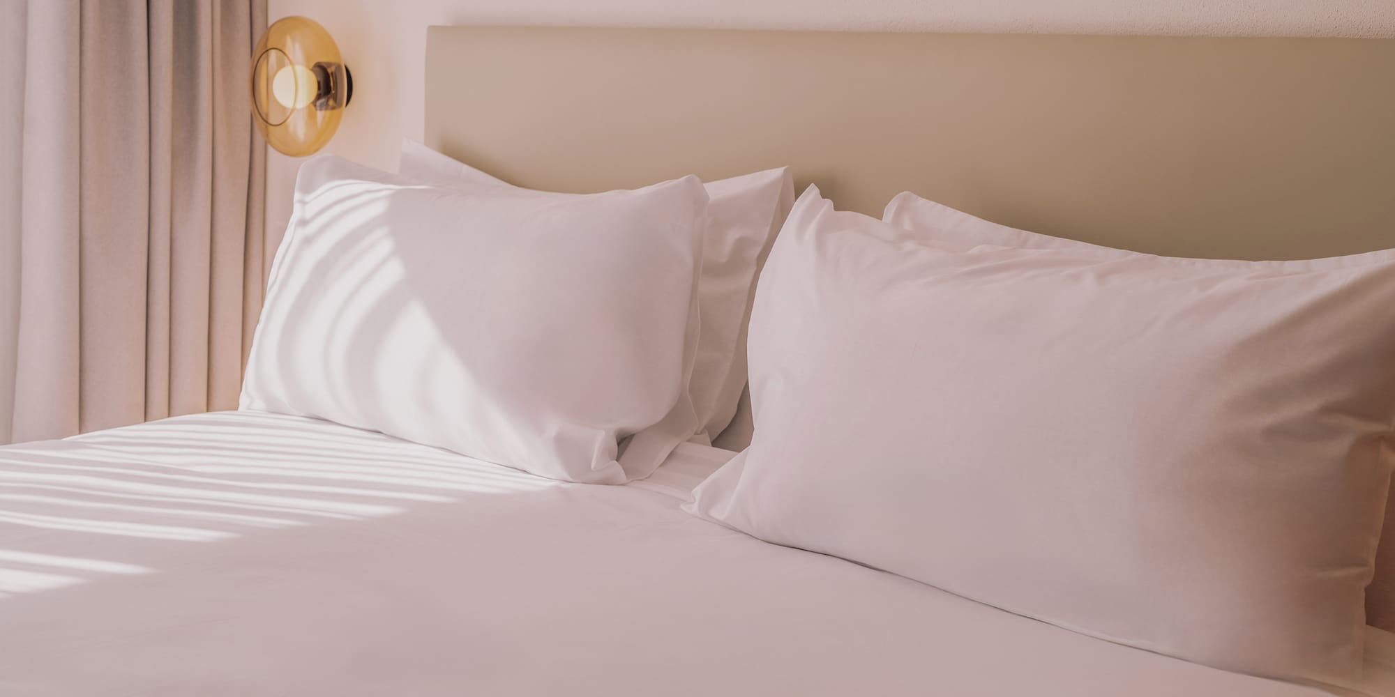 a bed with white sheets and pillows