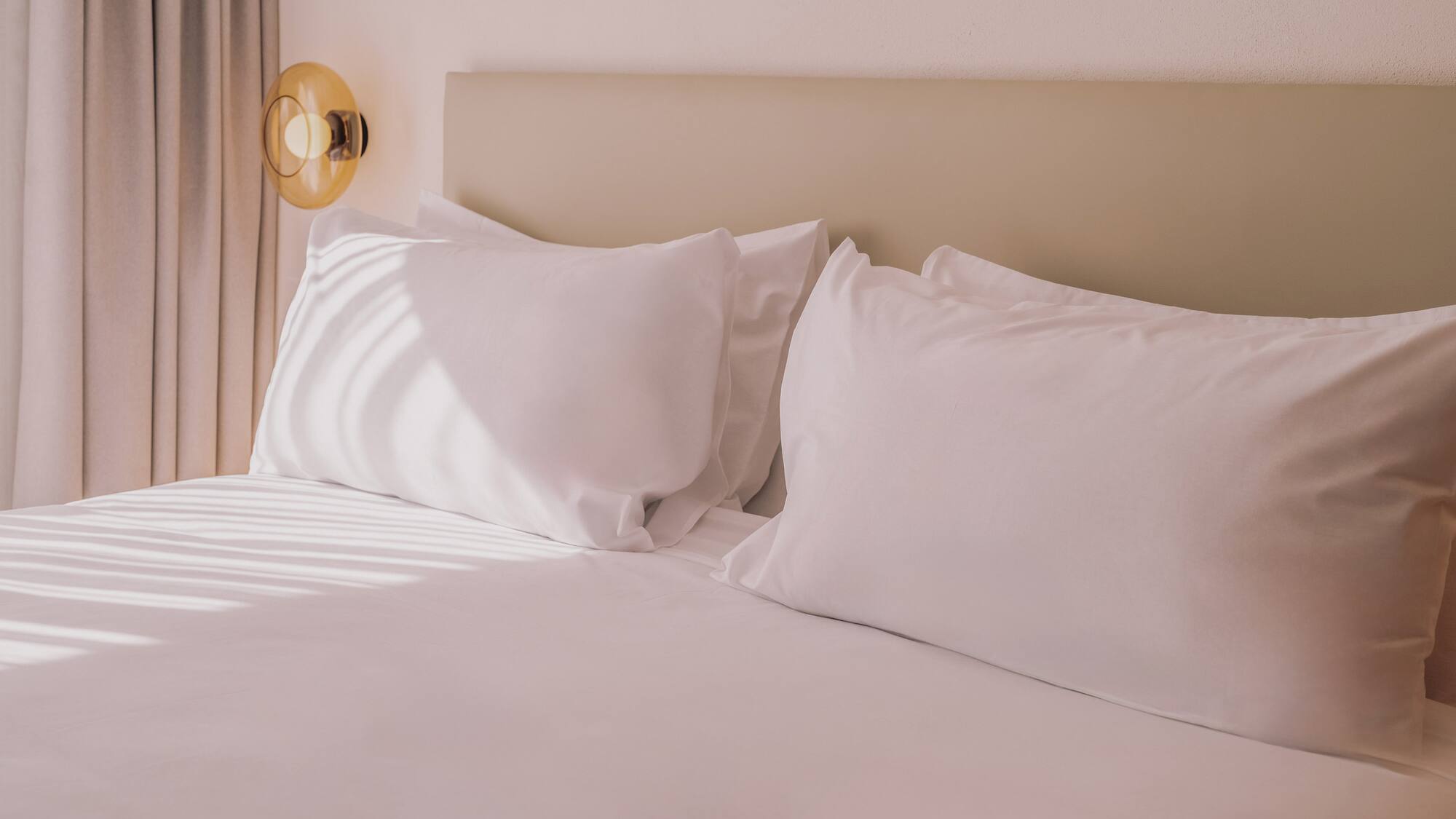 a bed with white sheets and pillows