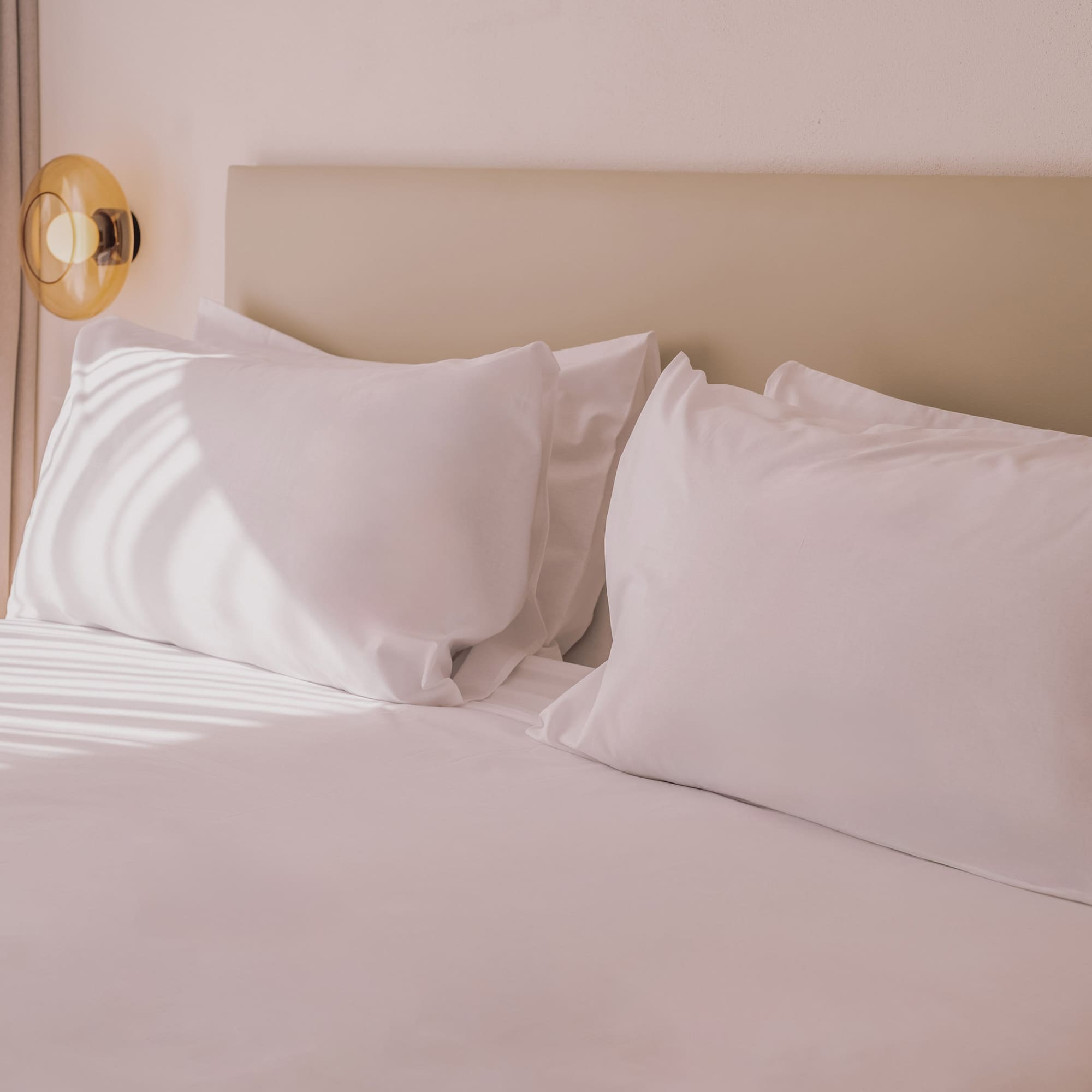 a bed with white sheets and pillows