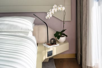 a white orchid on a nightstand next to a bed