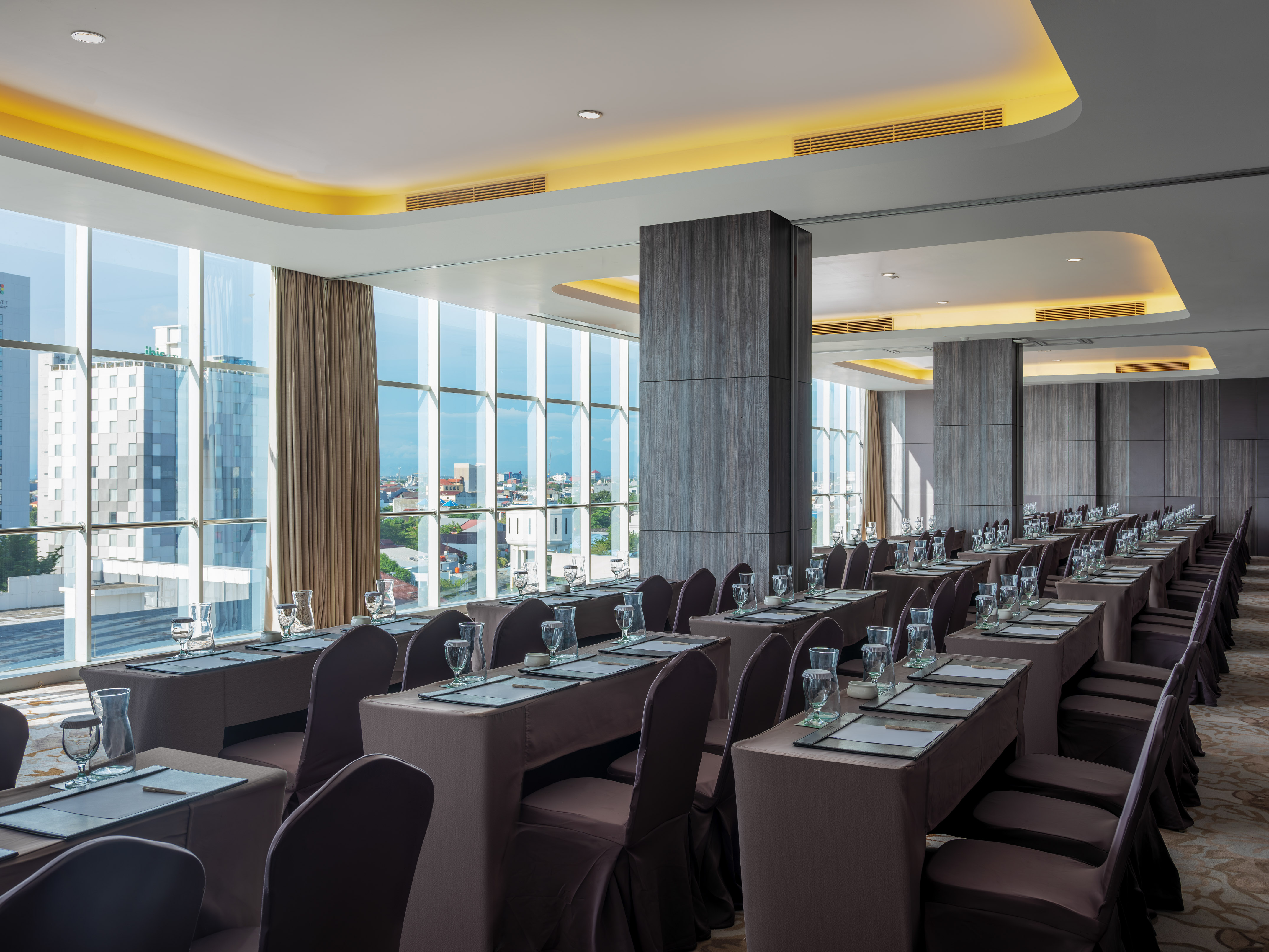 Modern meeting room with city view, rows of tables for business events.