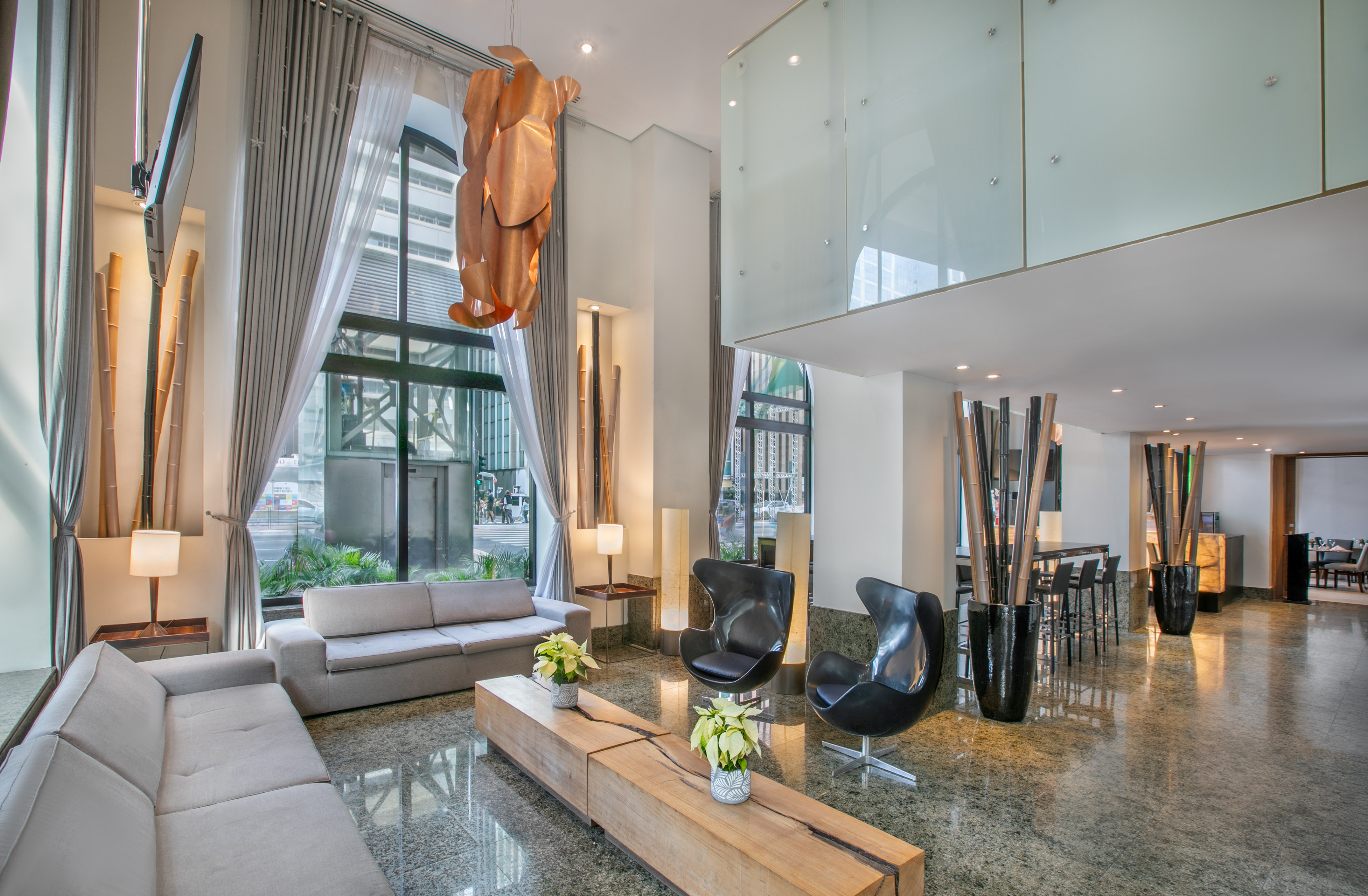 Contemporary hotel lobby with stylish seating, unique chandelier, and city views.
