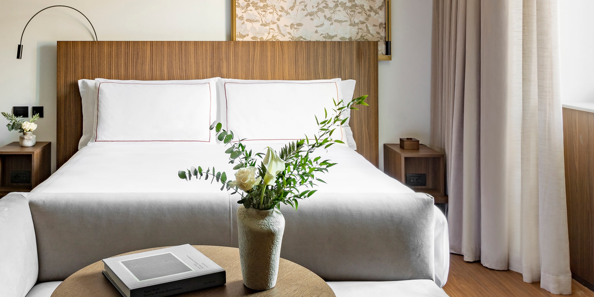 a vase of flowers on a table next to a bed