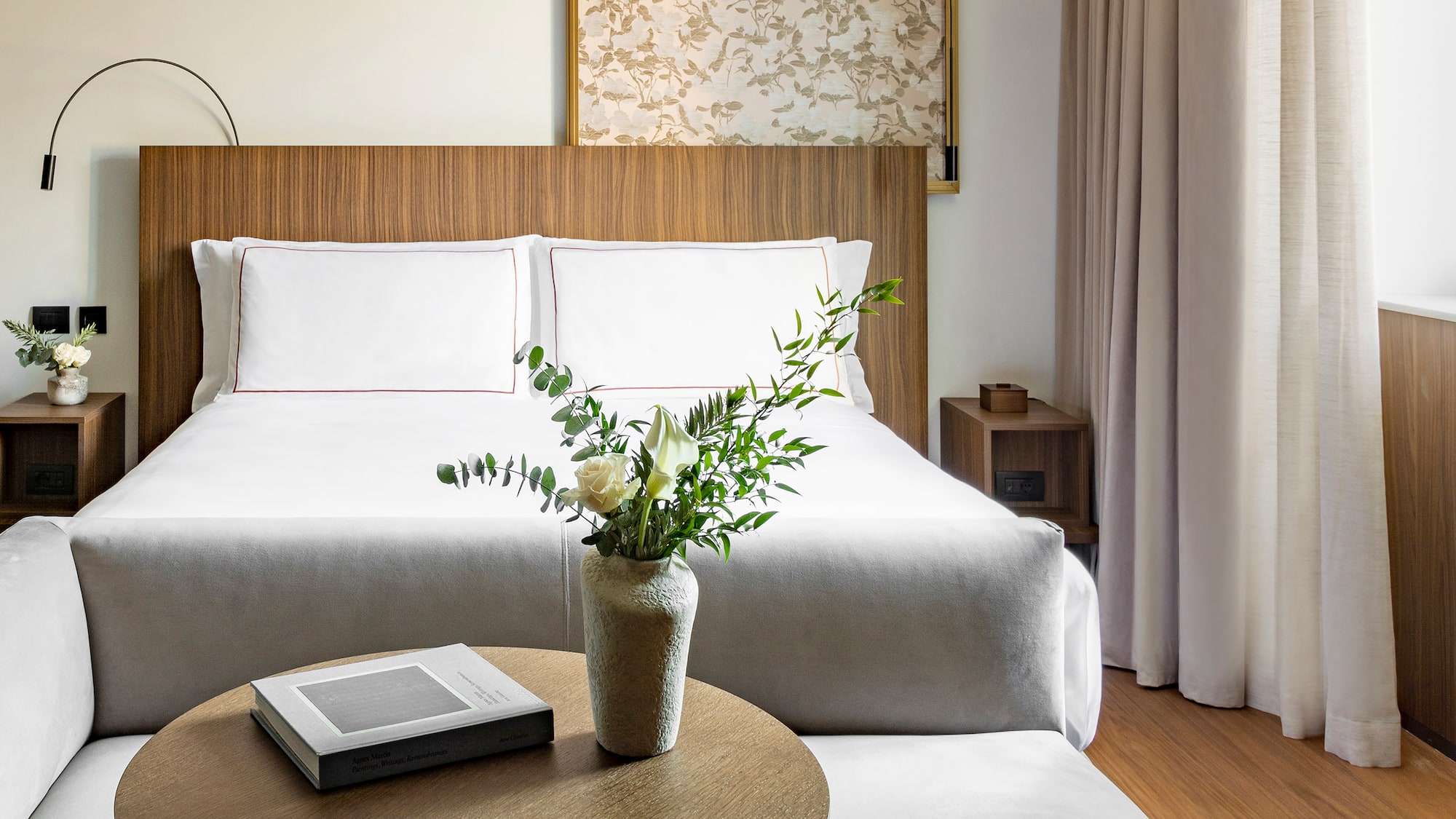 a vase of flowers on a table next to a bed