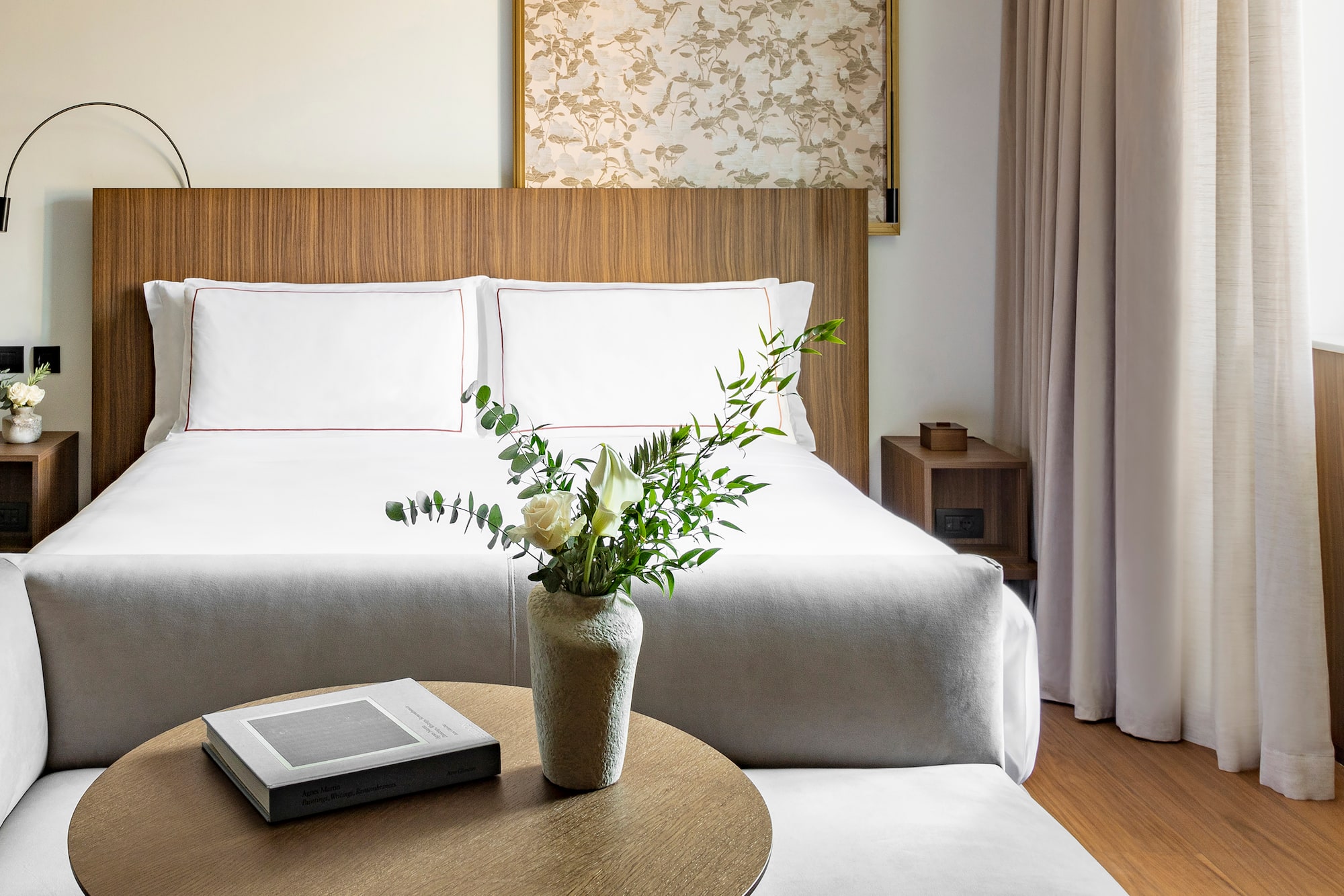 a vase of flowers on a table next to a bed