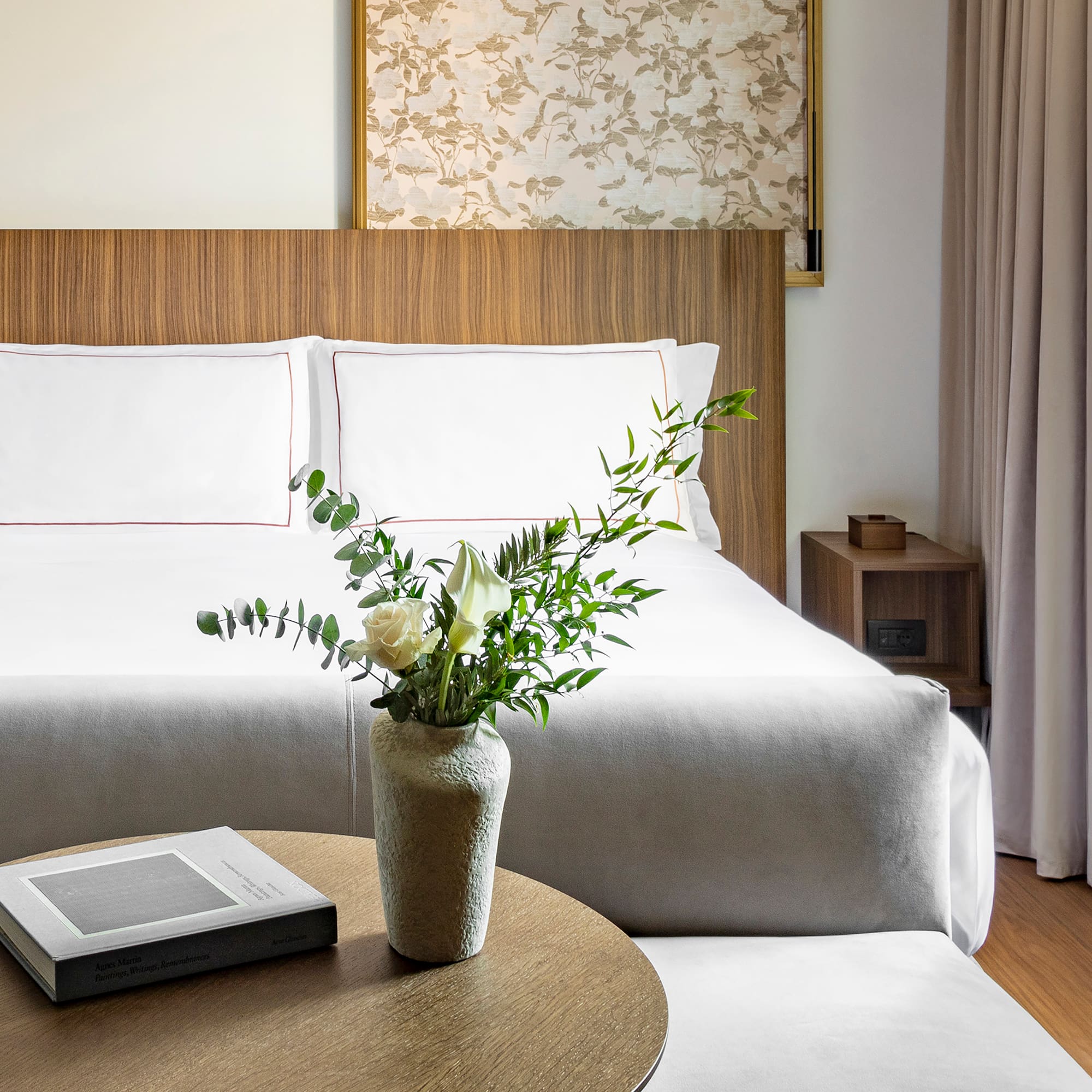 a vase of flowers on a table next to a bed