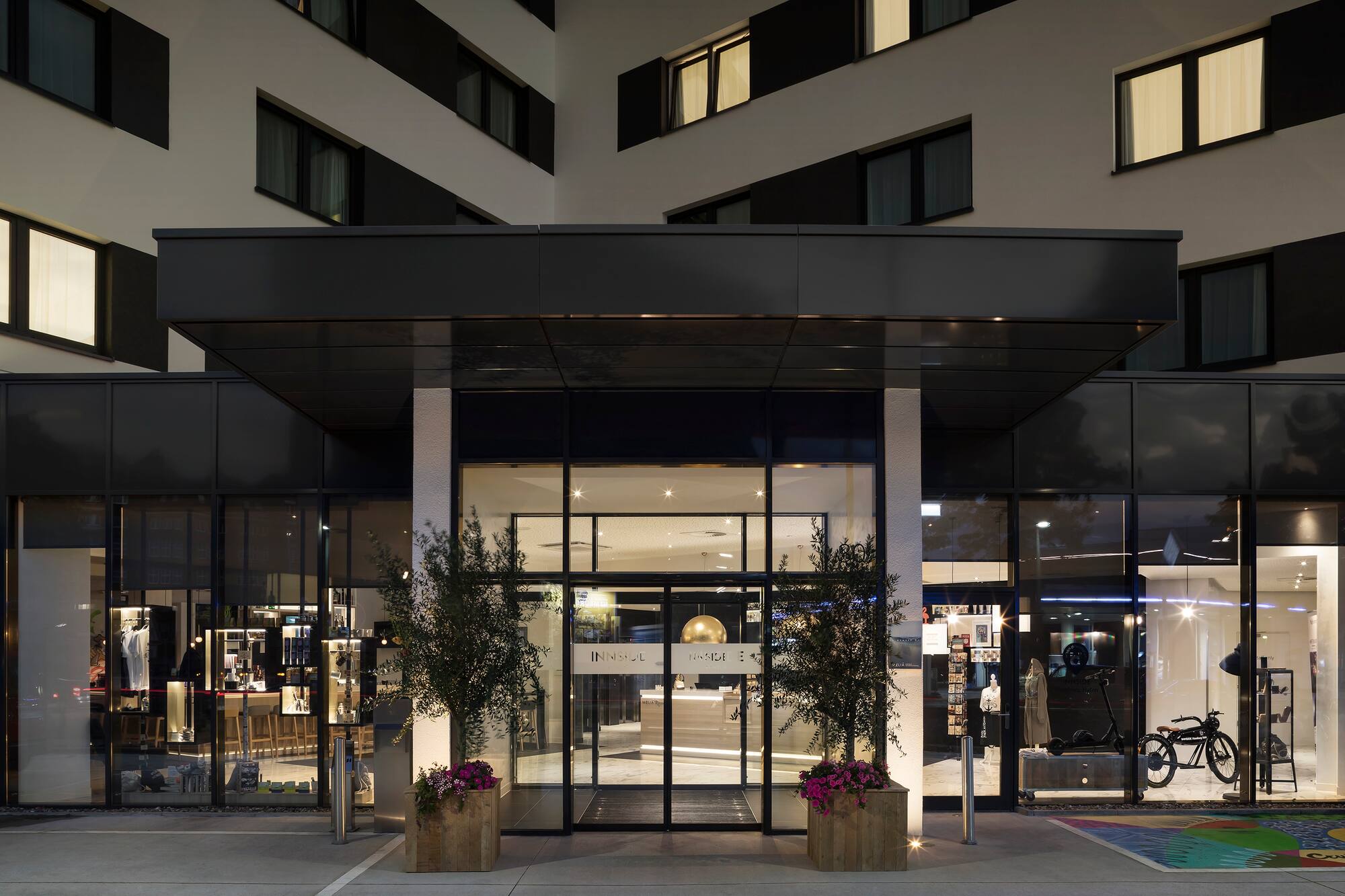 INNSiDE hotel entrance at night, modern building with illuminated glass lobby.