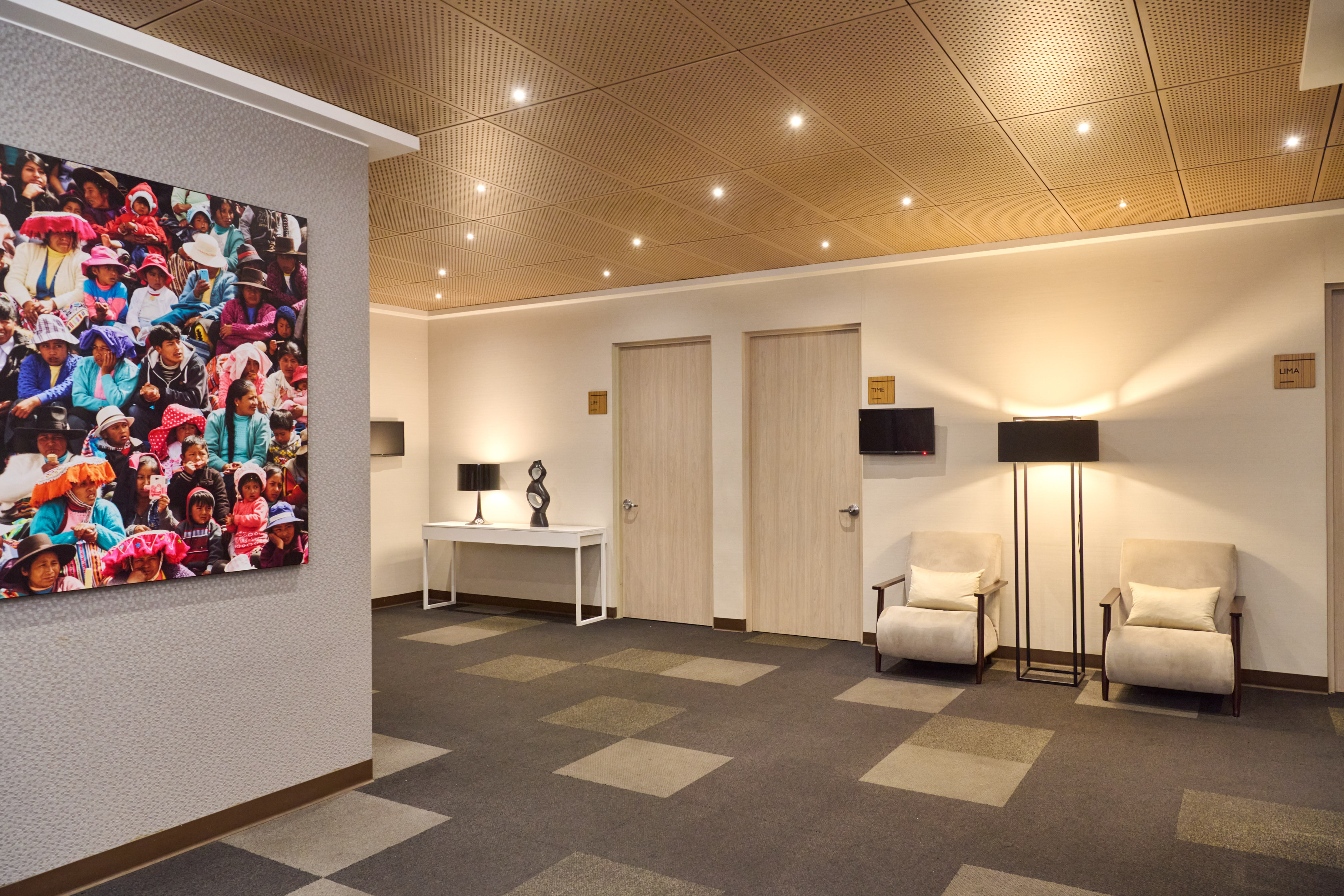 Modern hotel lobby with Peruvian art, conference doors, and cozy lounge seating.