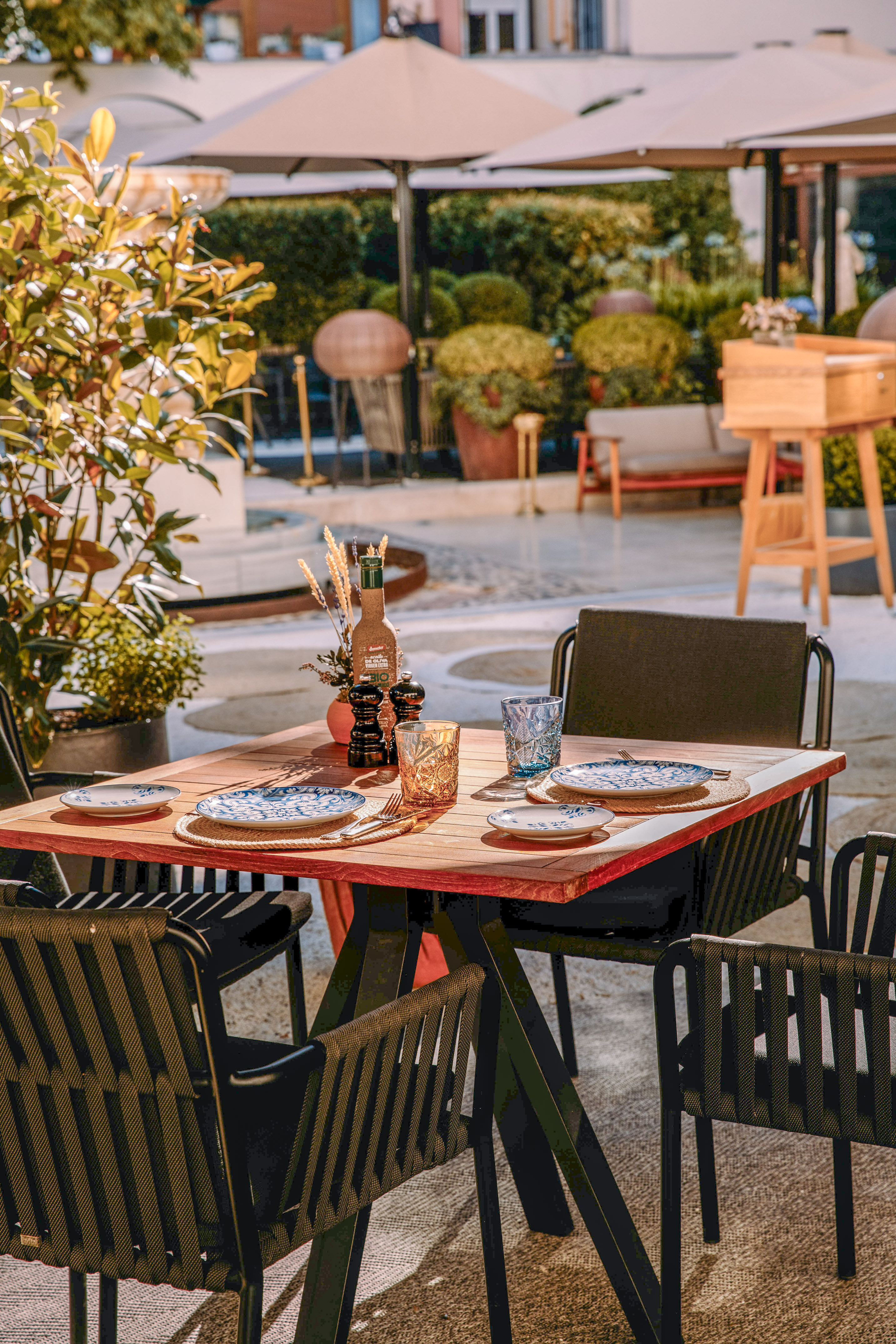Outdoor dining table set on a sunny patio with Mediterranean decor.