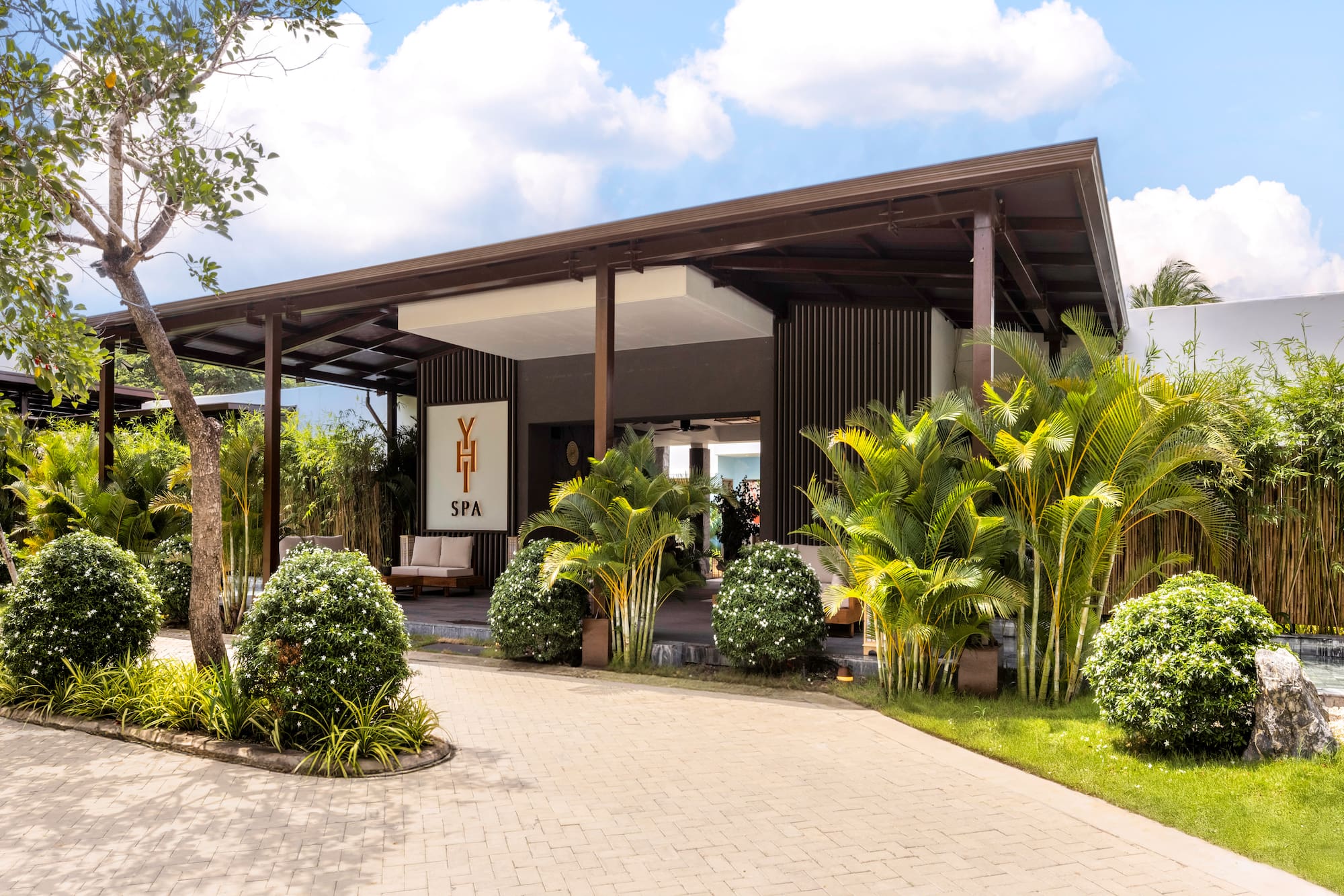 Tropical YHI SPA entrance, modern building with lush landscaping and paved drive.