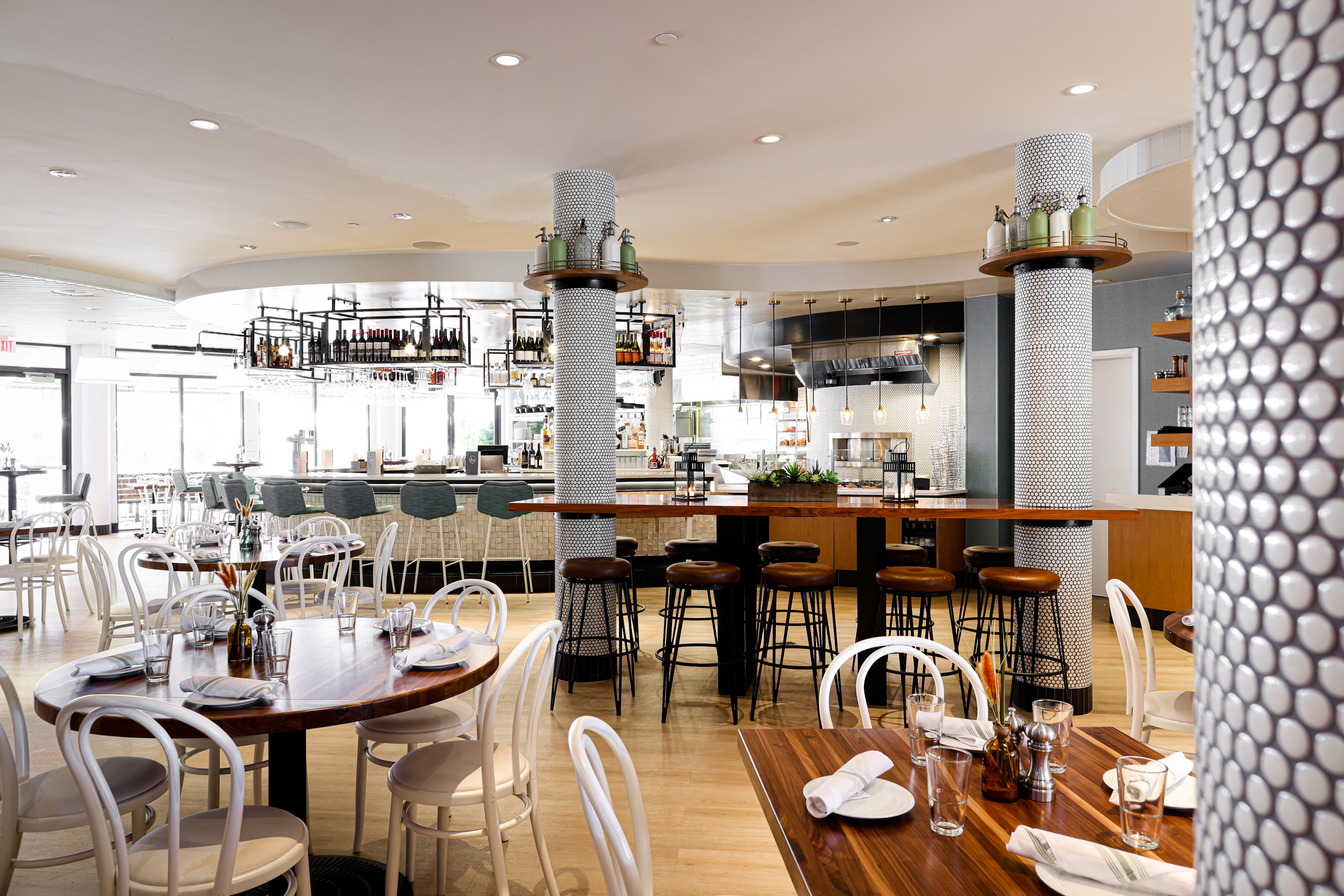 Modern restaurant interior with dining tables, bar area, and striking tiled columns.