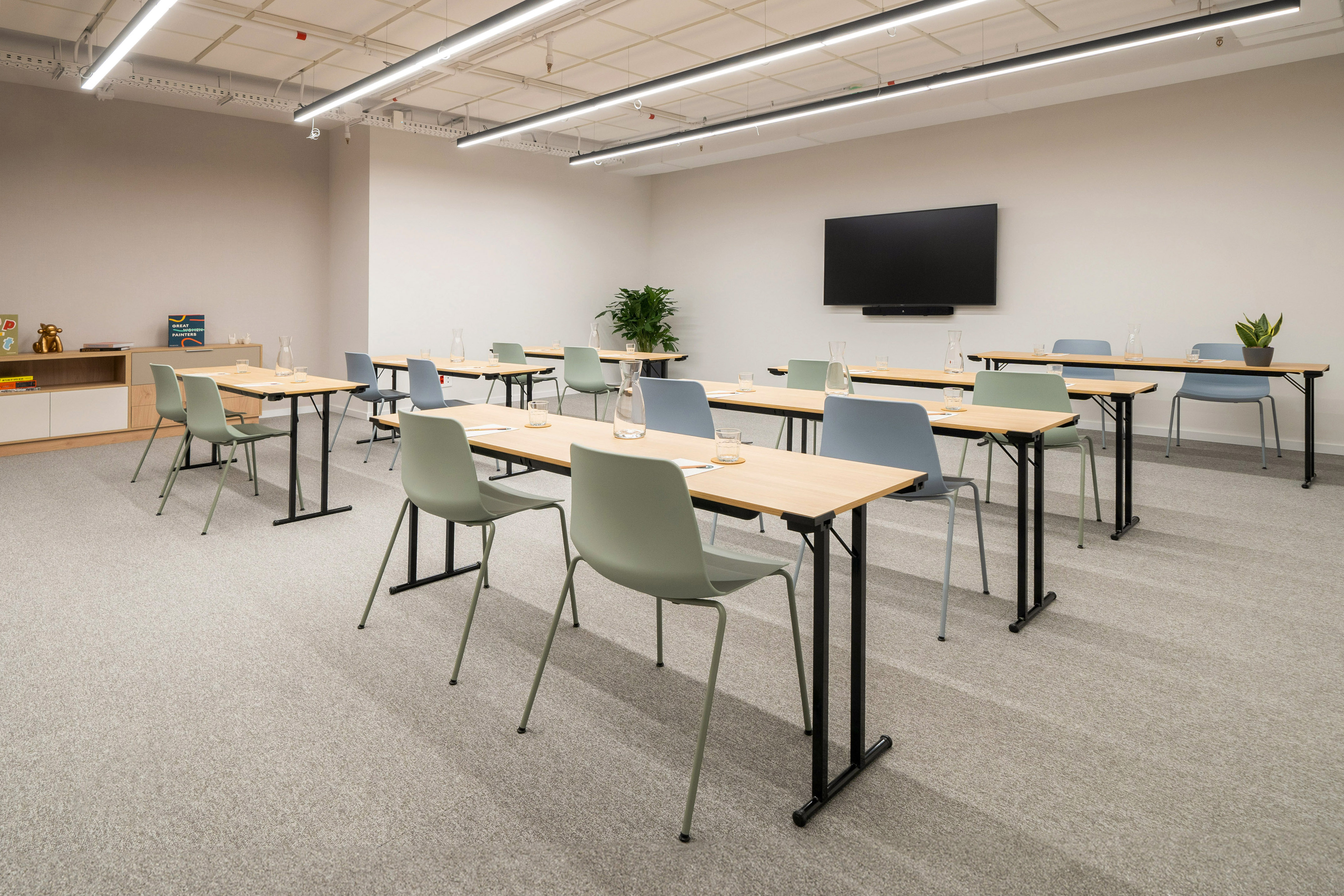 Bright training room with light wood tables, colorful chairs, and wall screen.