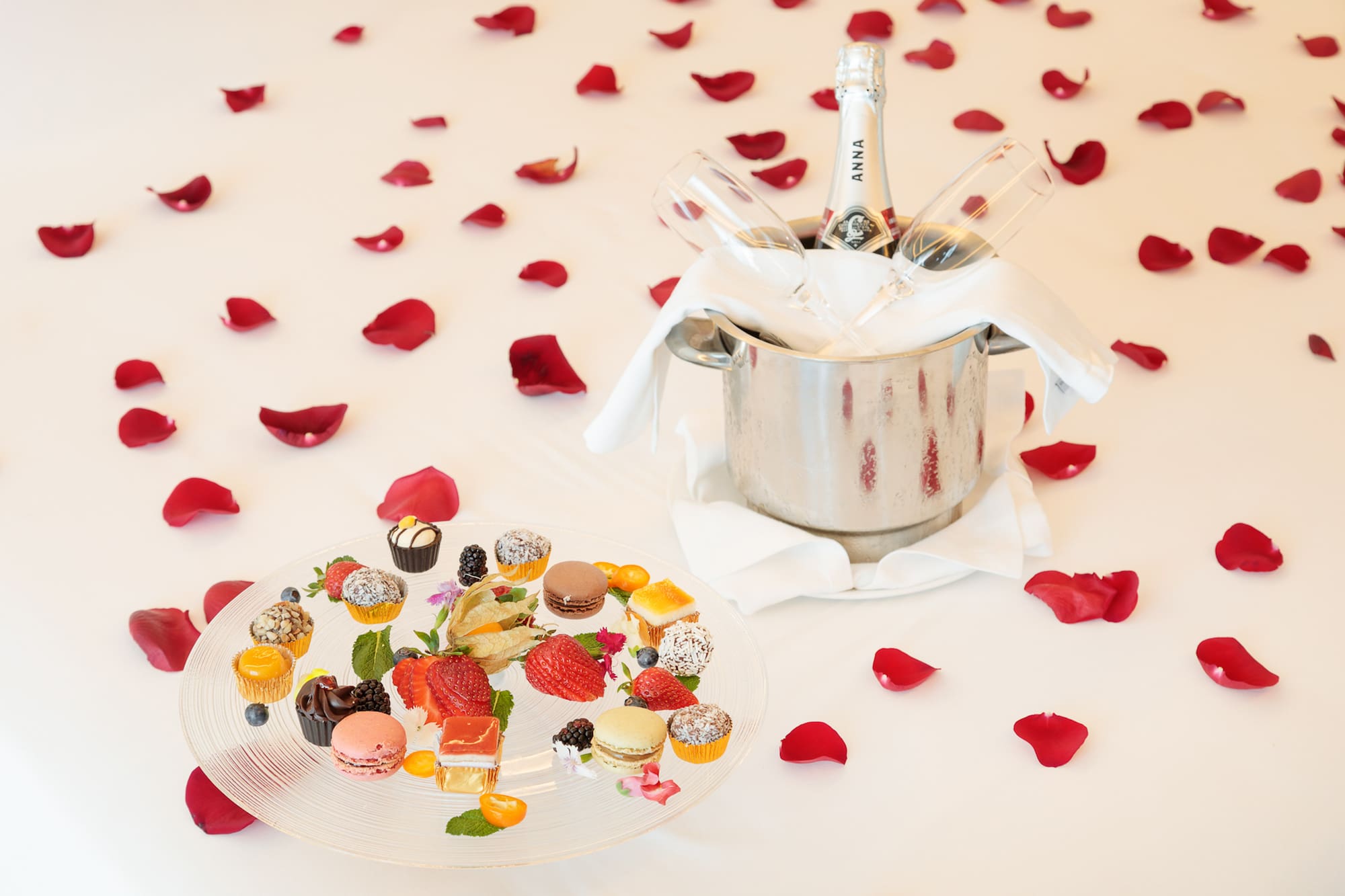 a champagne bottle in a bucket next to a plate of desserts
