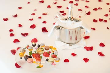 a champagne bottle in a bucket next to a plate of desserts