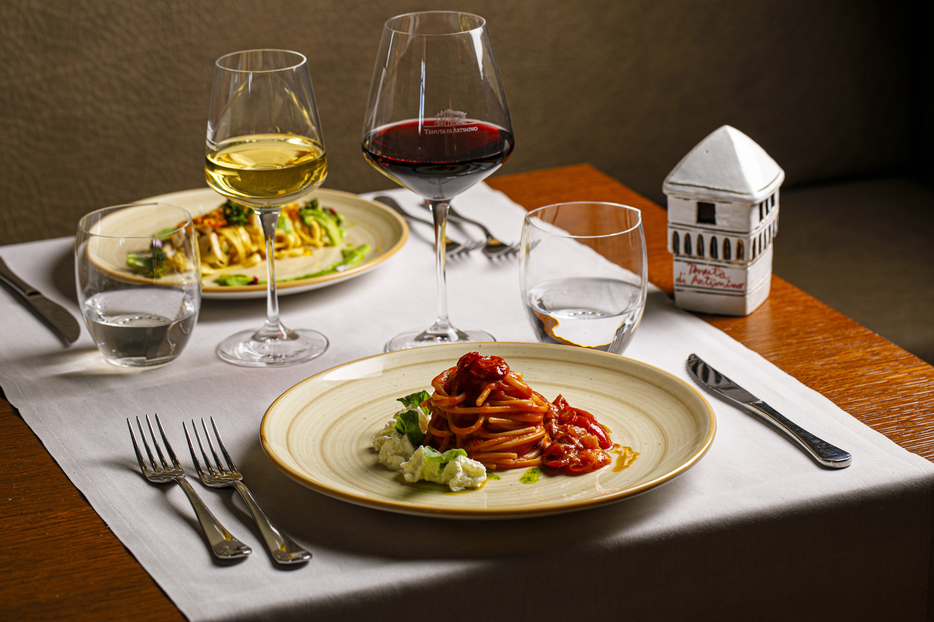 Fine dining pasta and wine meal, featuring spaghetti with tomato sauce.