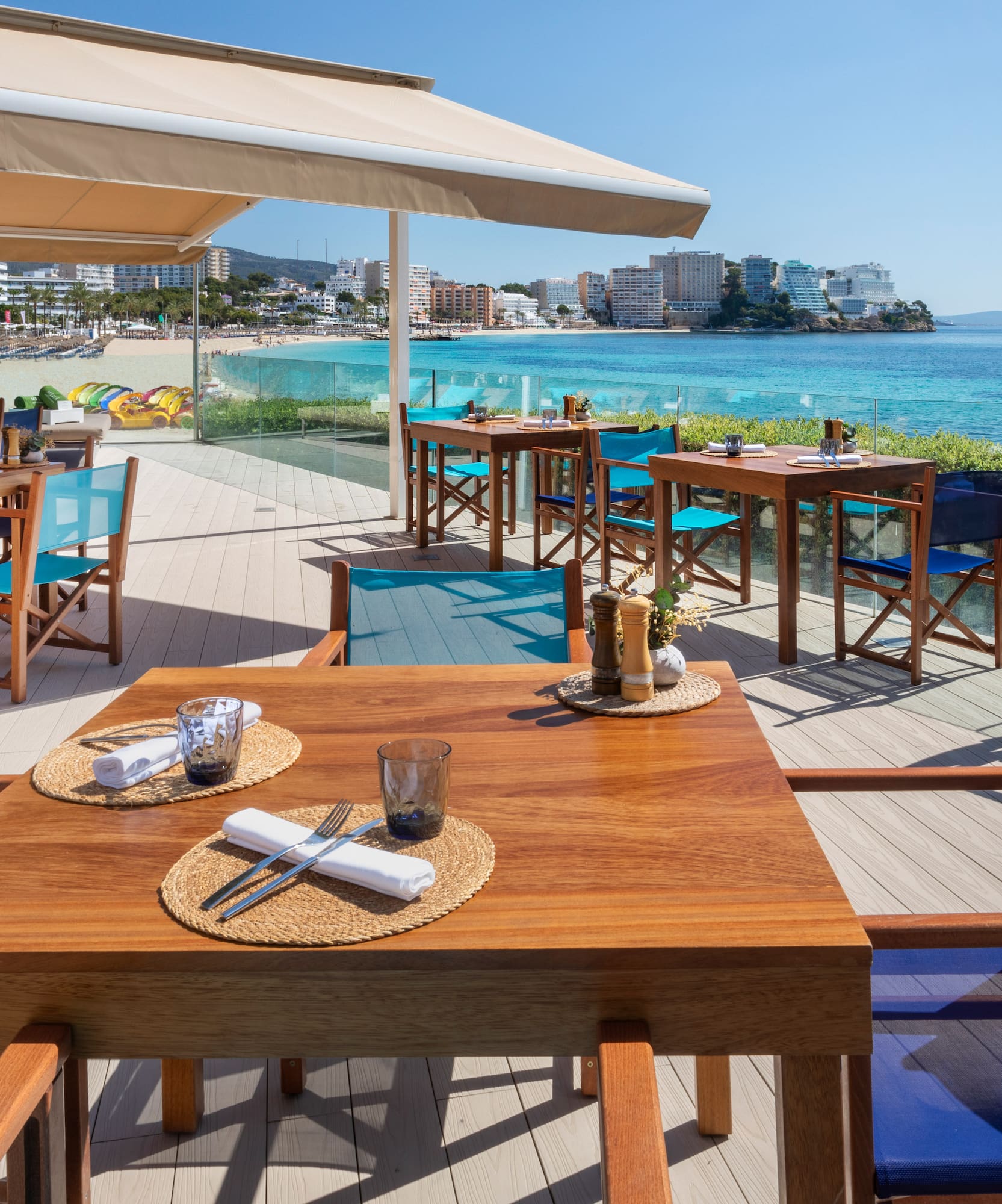 a table and chairs on a deck overlooking a beach