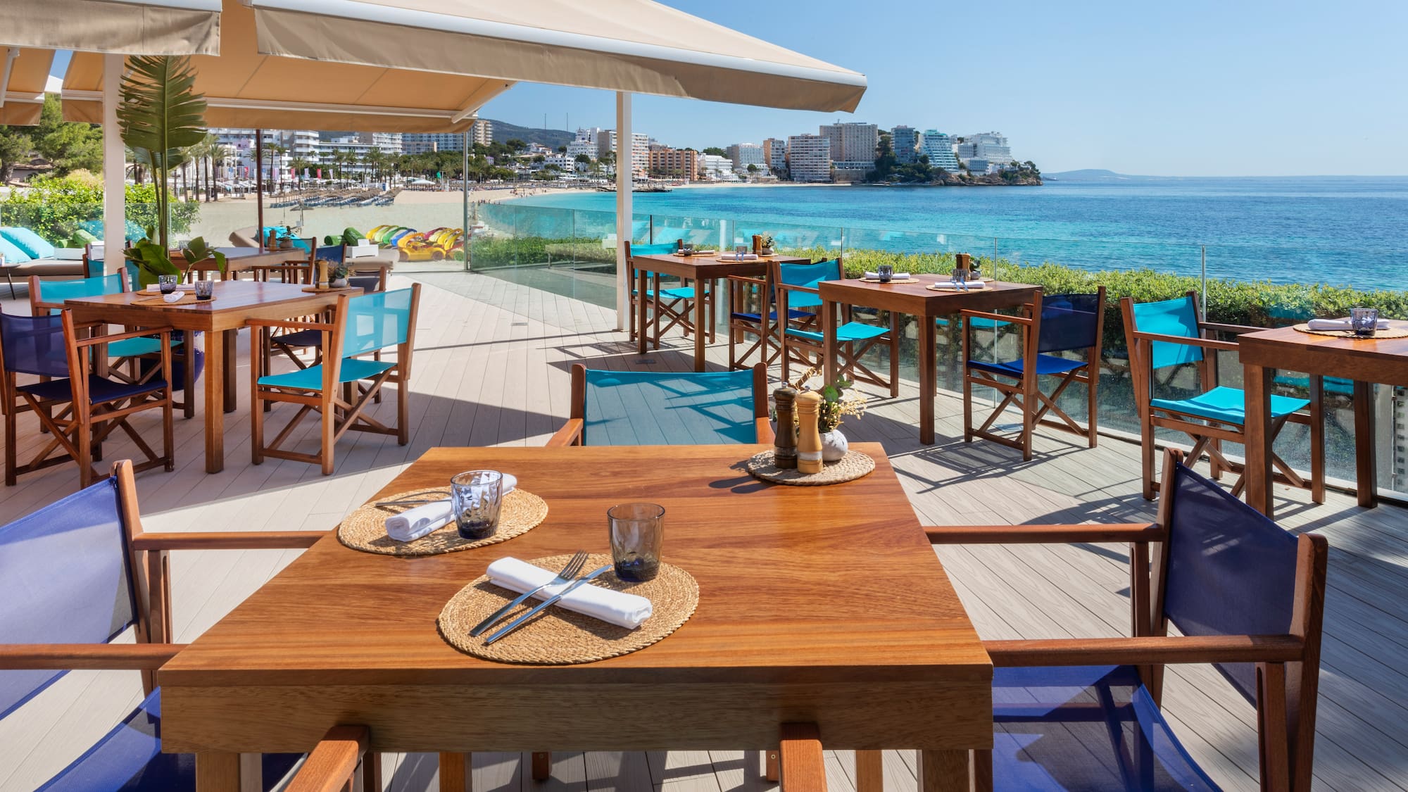 a table and chairs on a deck overlooking a beach