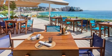 a table and chairs on a deck overlooking a beach