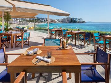 a table and chairs on a deck overlooking a beach