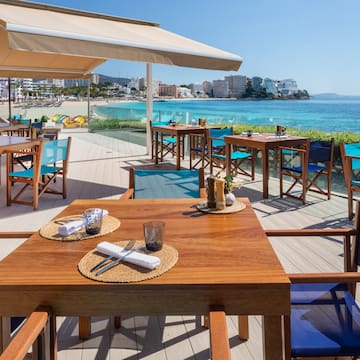 a table and chairs on a deck overlooking a beach