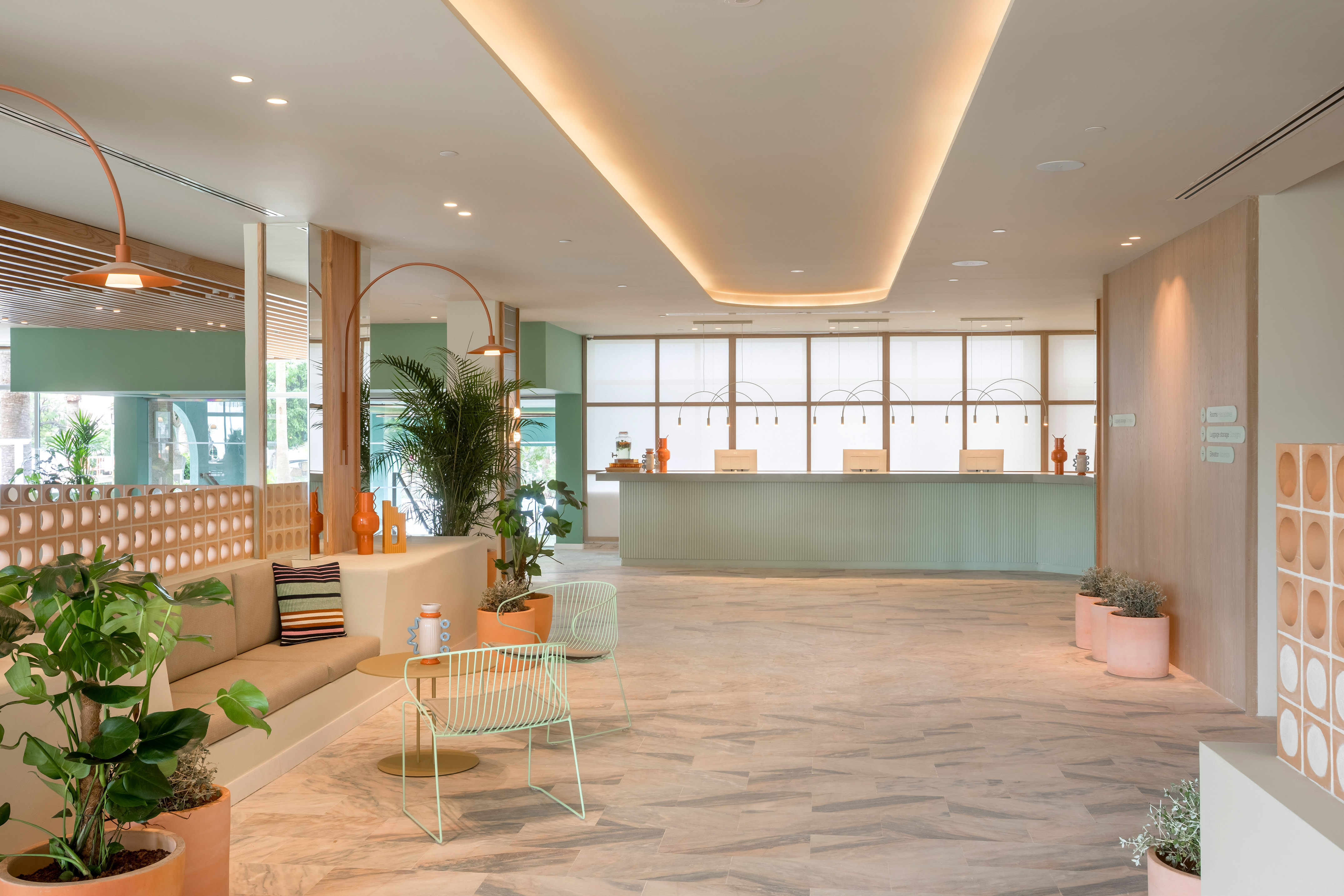 Modern hotel lobby with mint reception desk, contemporary seating, and plants.