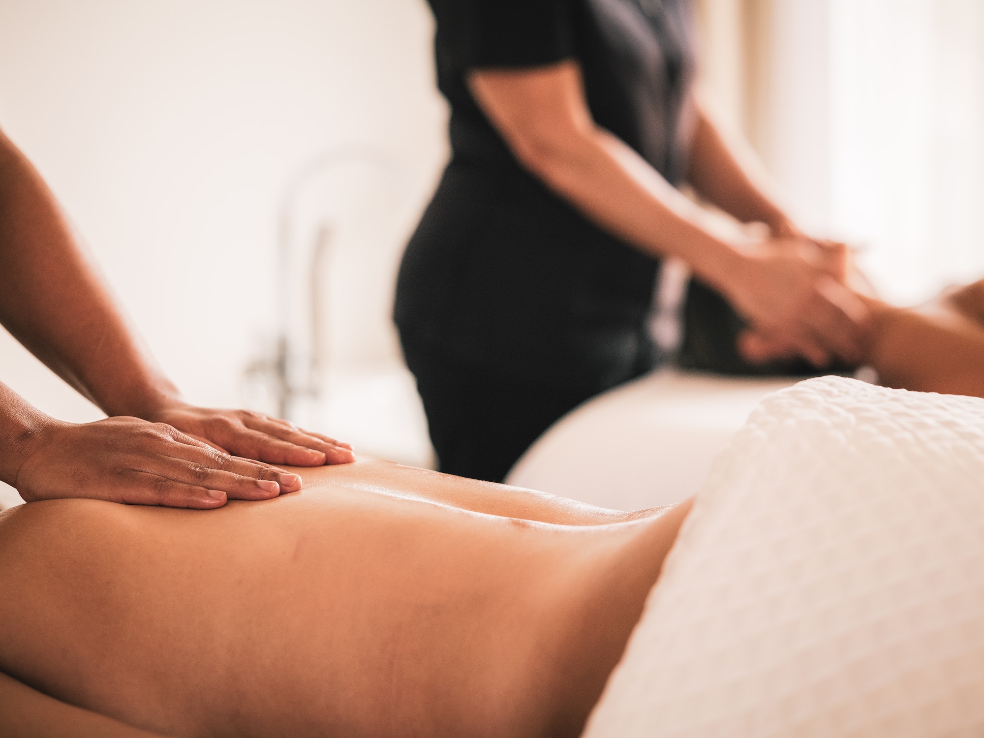 Hands giving a back massage to a person in a serene spa.
