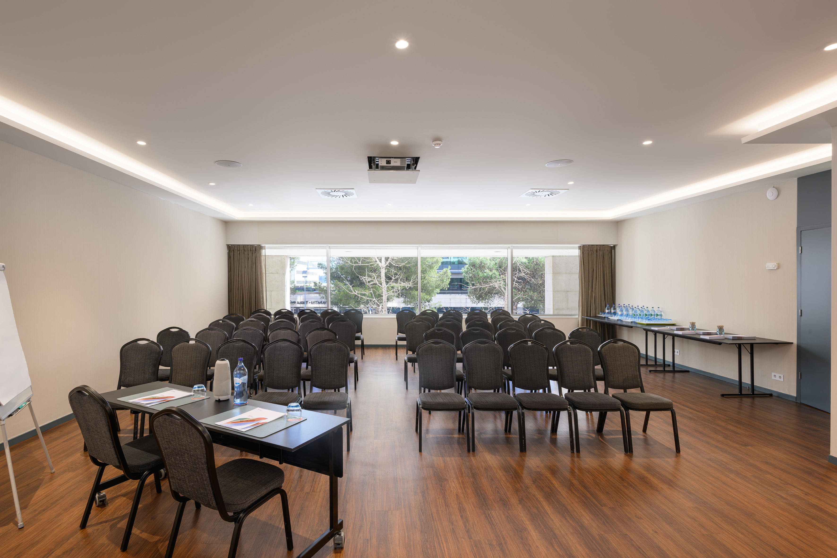 Empty conference room with theater seating, projector, and large windows.