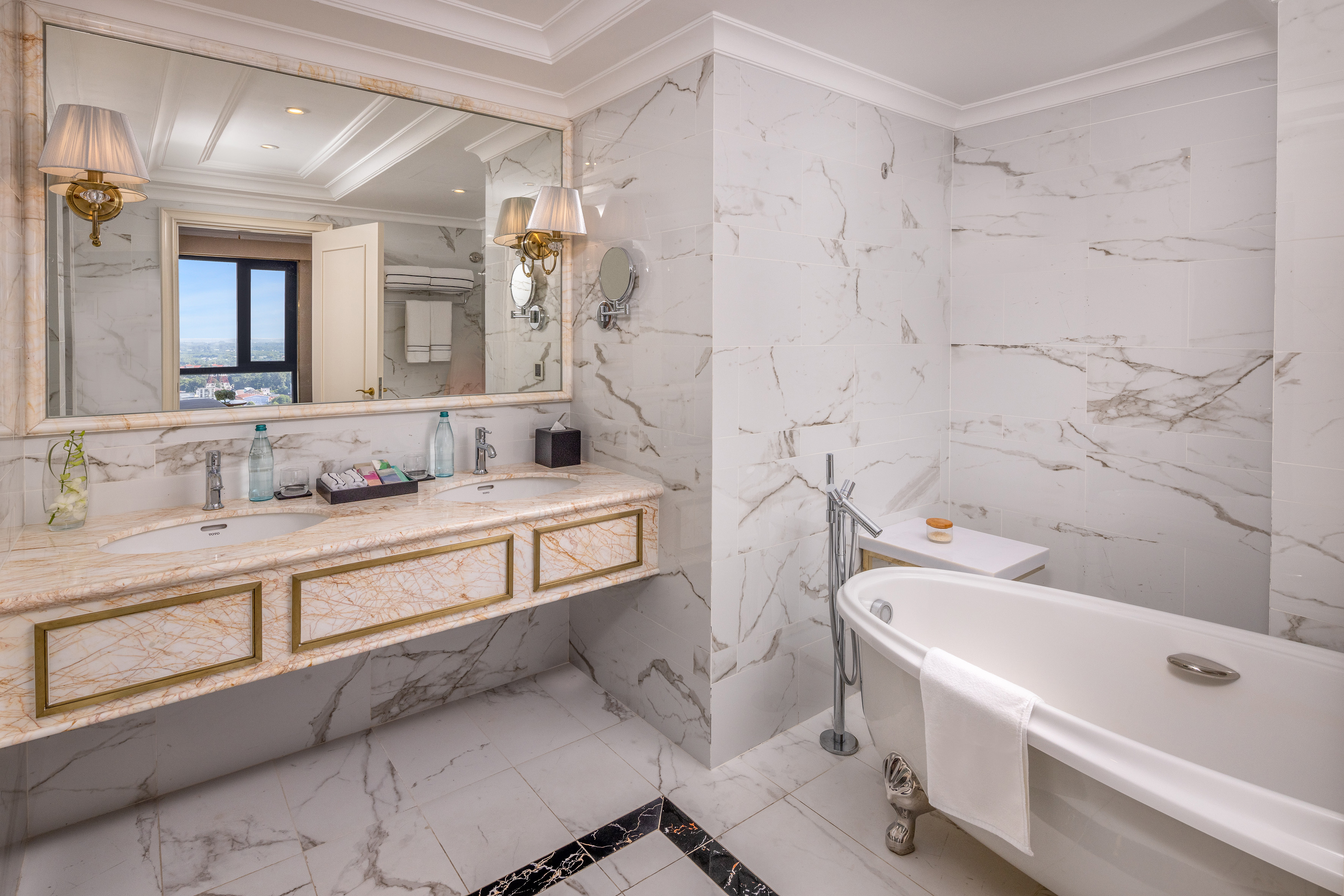 Elegant marble bathroom with double vanity, freestanding tub, and gold accents.
